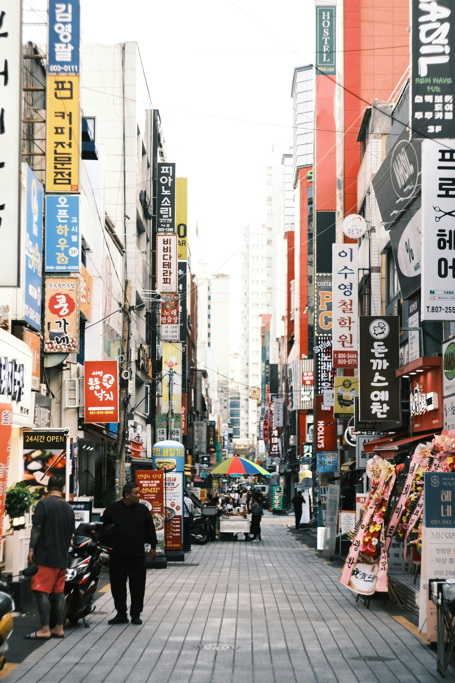 韓国の路地に並ぶ看板と人のいる商店街の通り