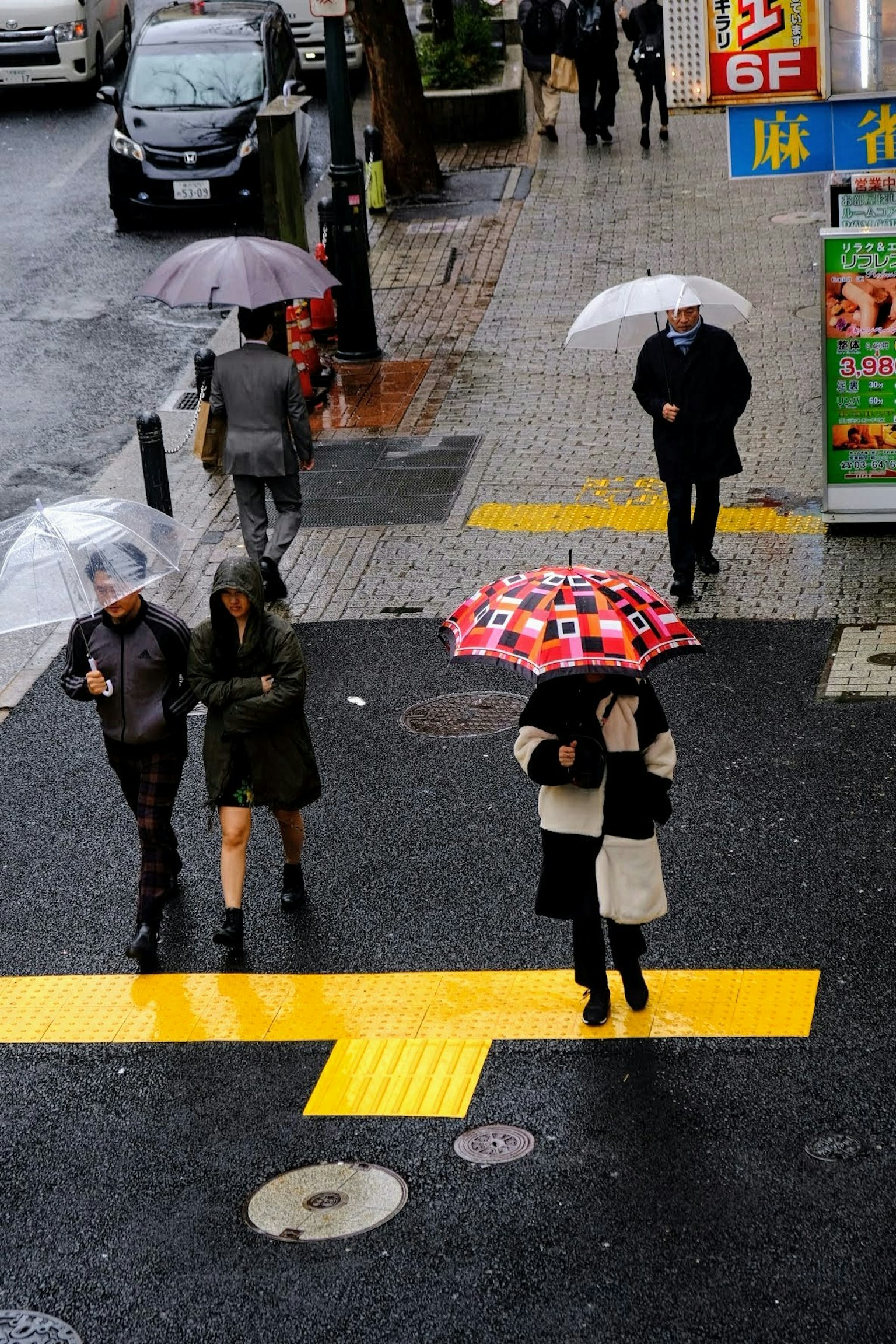 人们在雨中撑着伞过马路