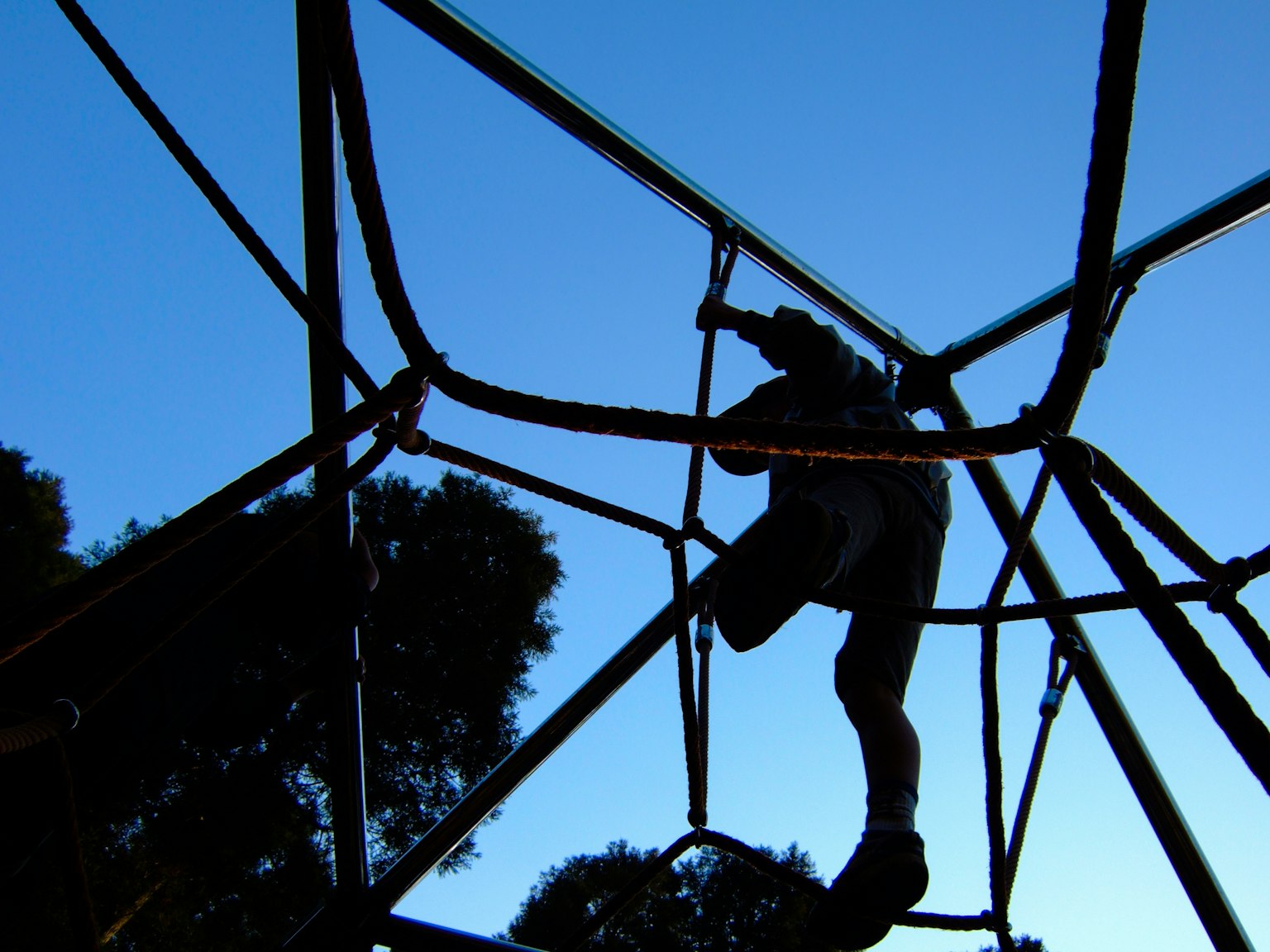 Silhouette d'un enfant grimpant sur un équipement de jeu