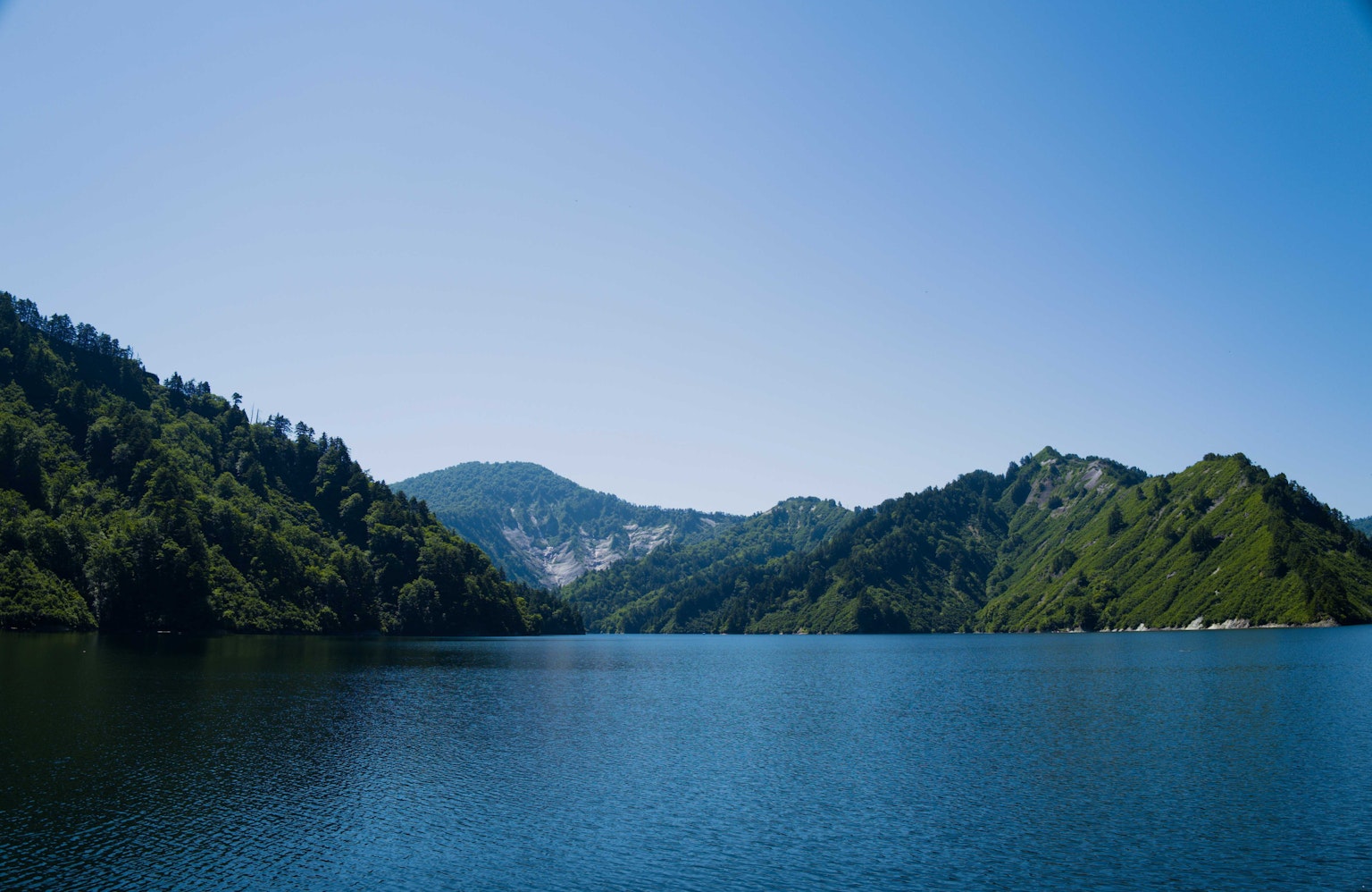 Vue panoramique d'un lac bleu entouré de montagnes vertes
