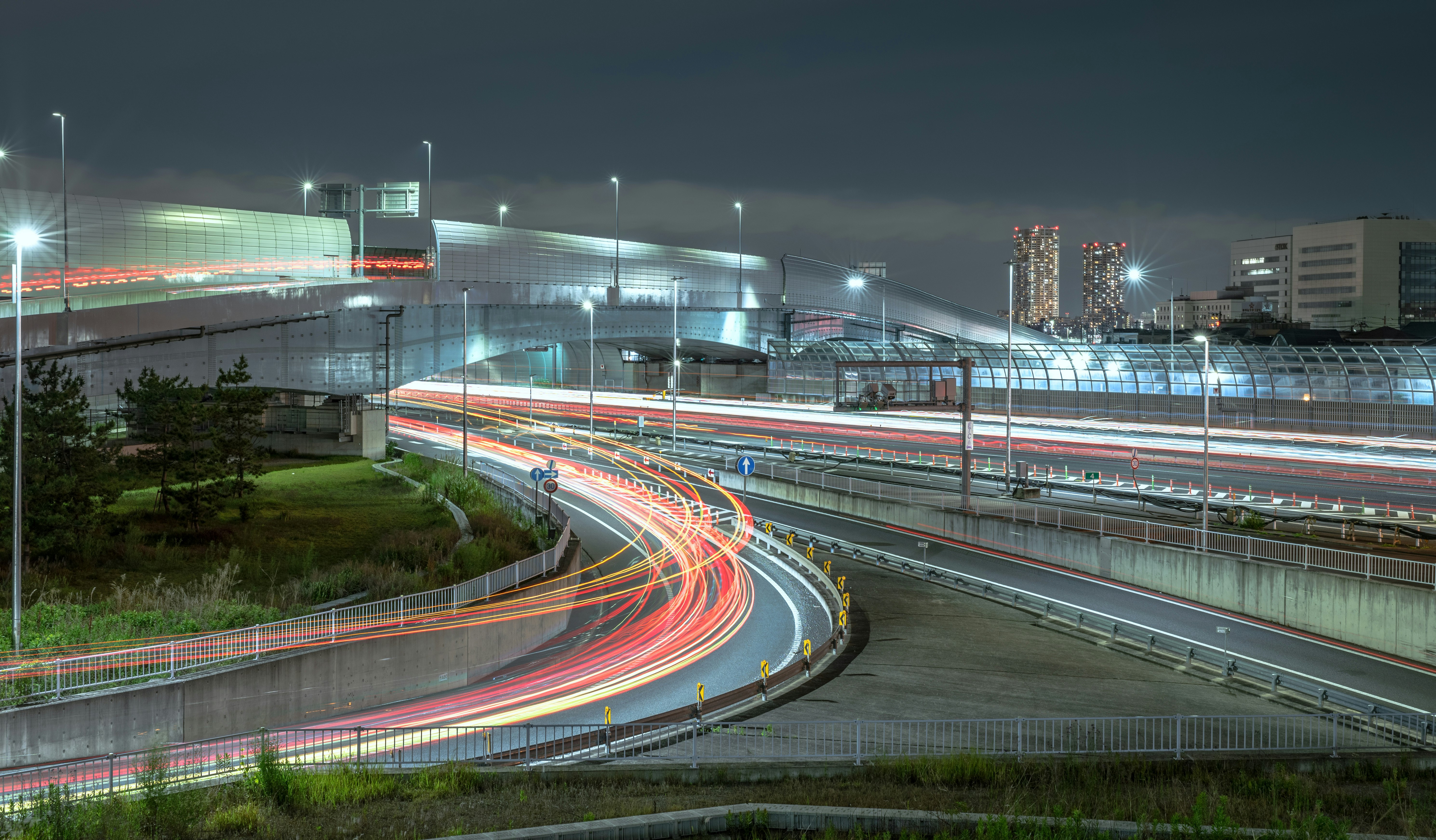 Image de nuit en pose longue avec des traces lumineuses sur une bretelle d’autoroute en courbe