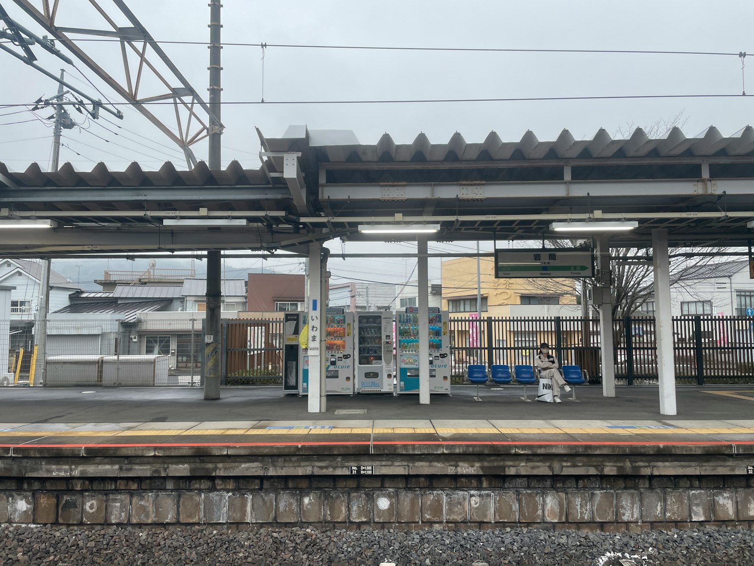 Plateforme de gare avec des distributeurs automatiques sous la pluie