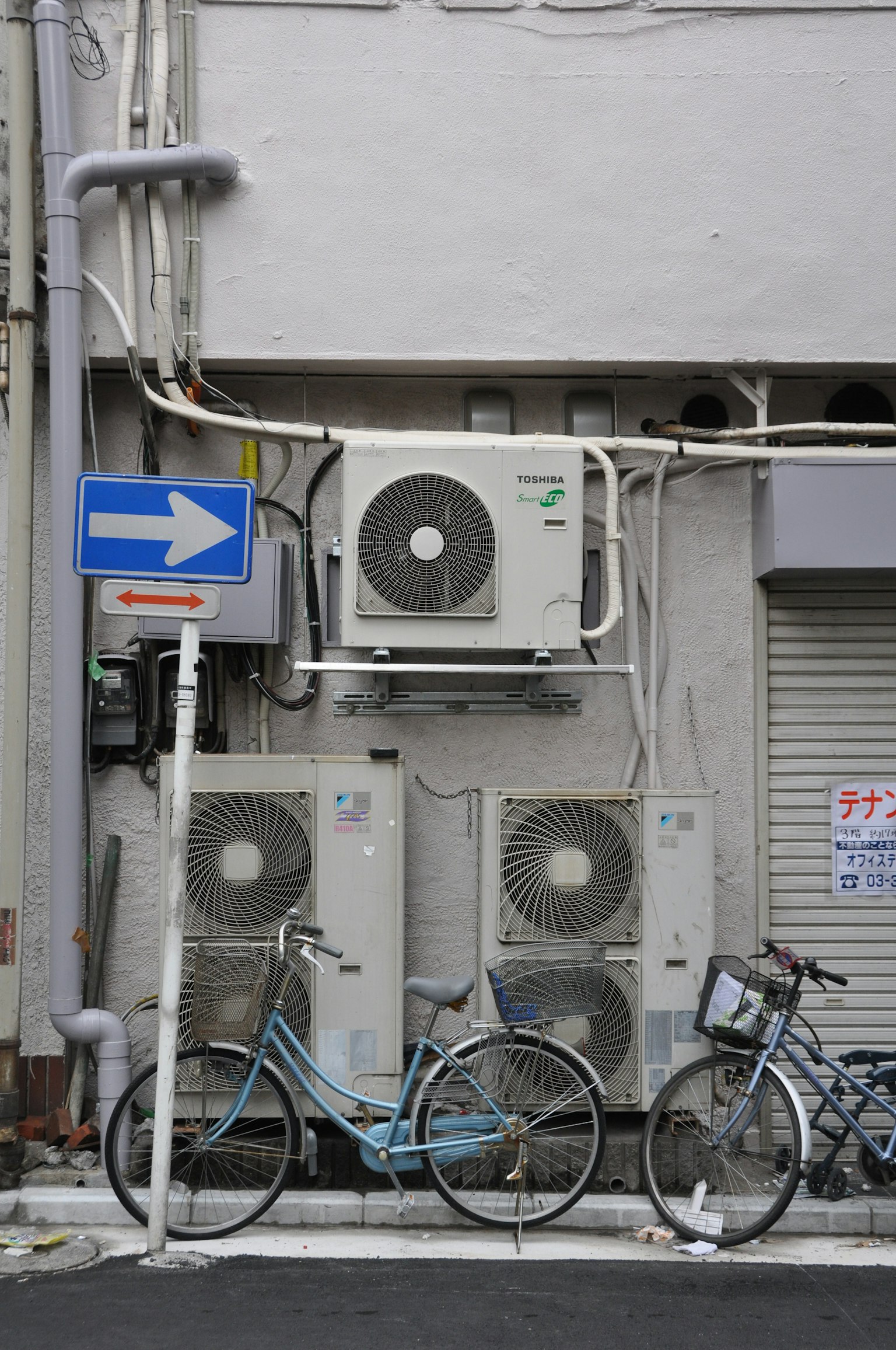 Scena di angolo di strada con unità di condizionamento su un muro bianco e biciclette blu