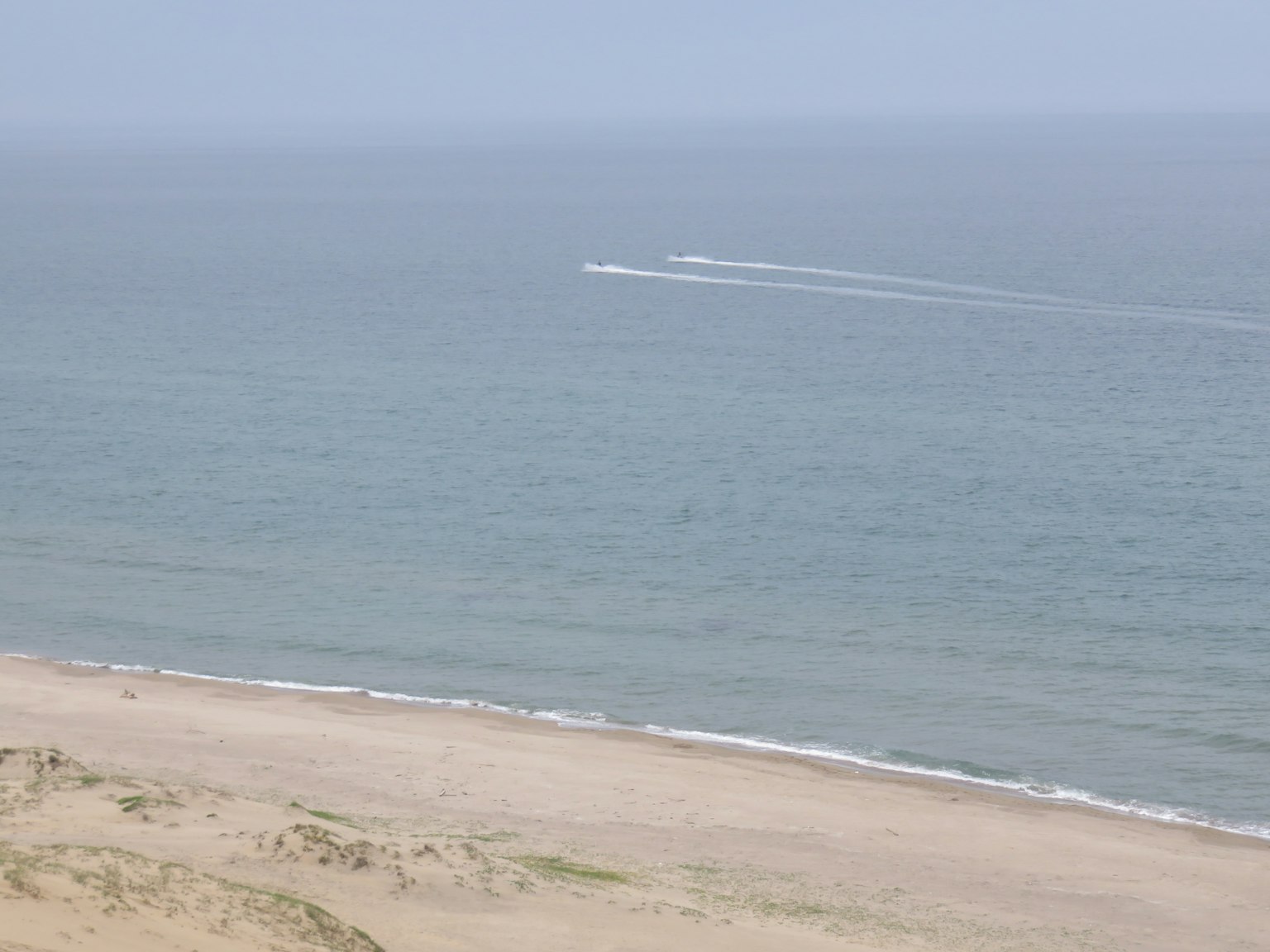 Vista escénica del océano y la playa con la estela de un bote