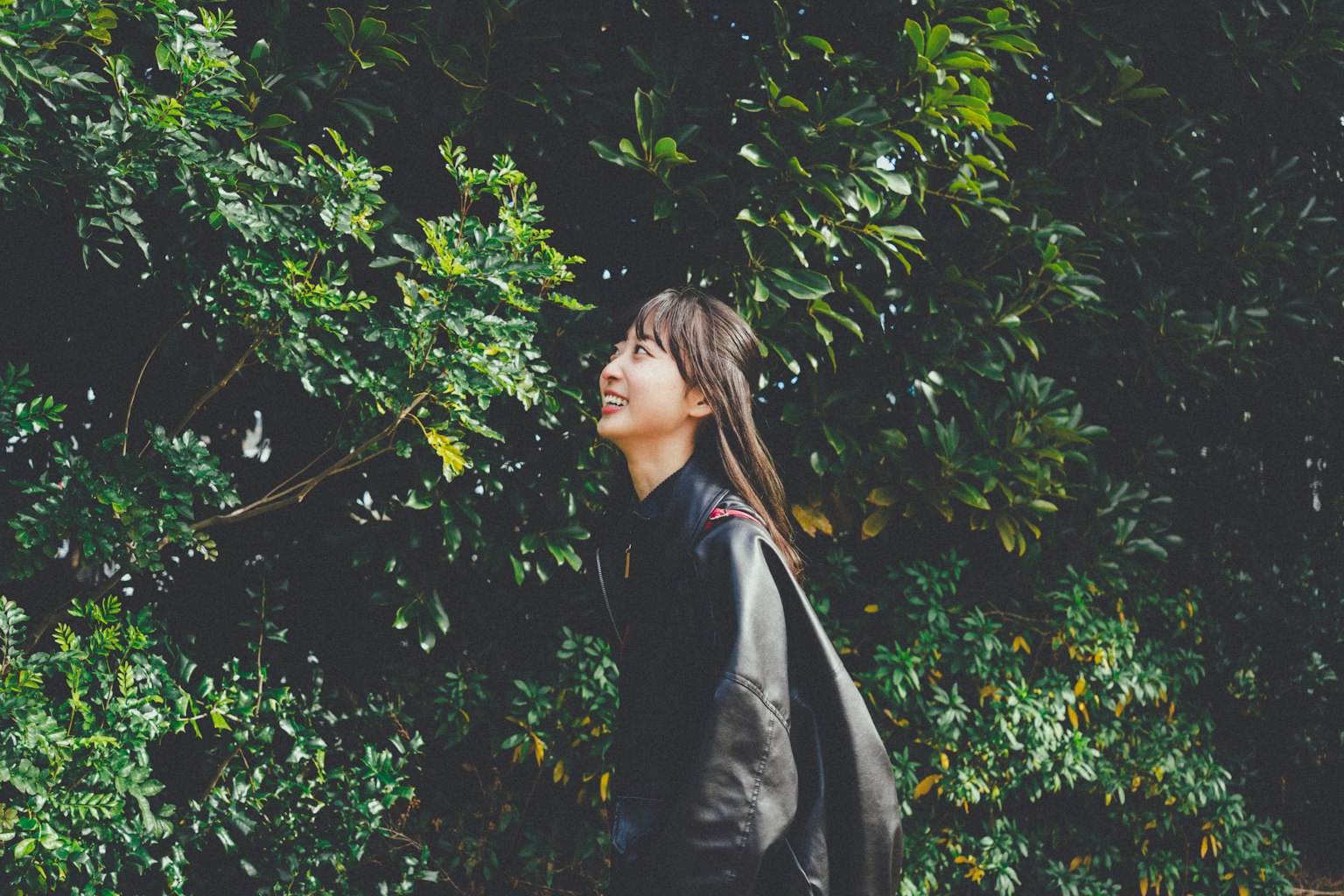 Side profile of a smiling woman against a green background