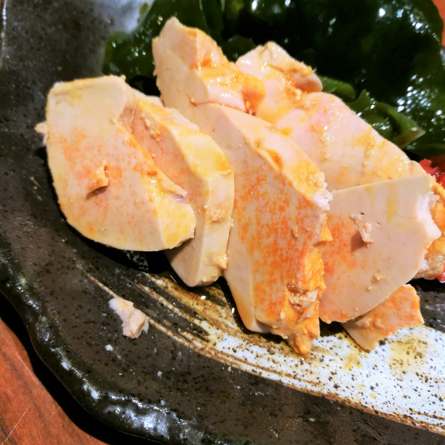 切片鸡肉与海藻一起放在黑色盘子上