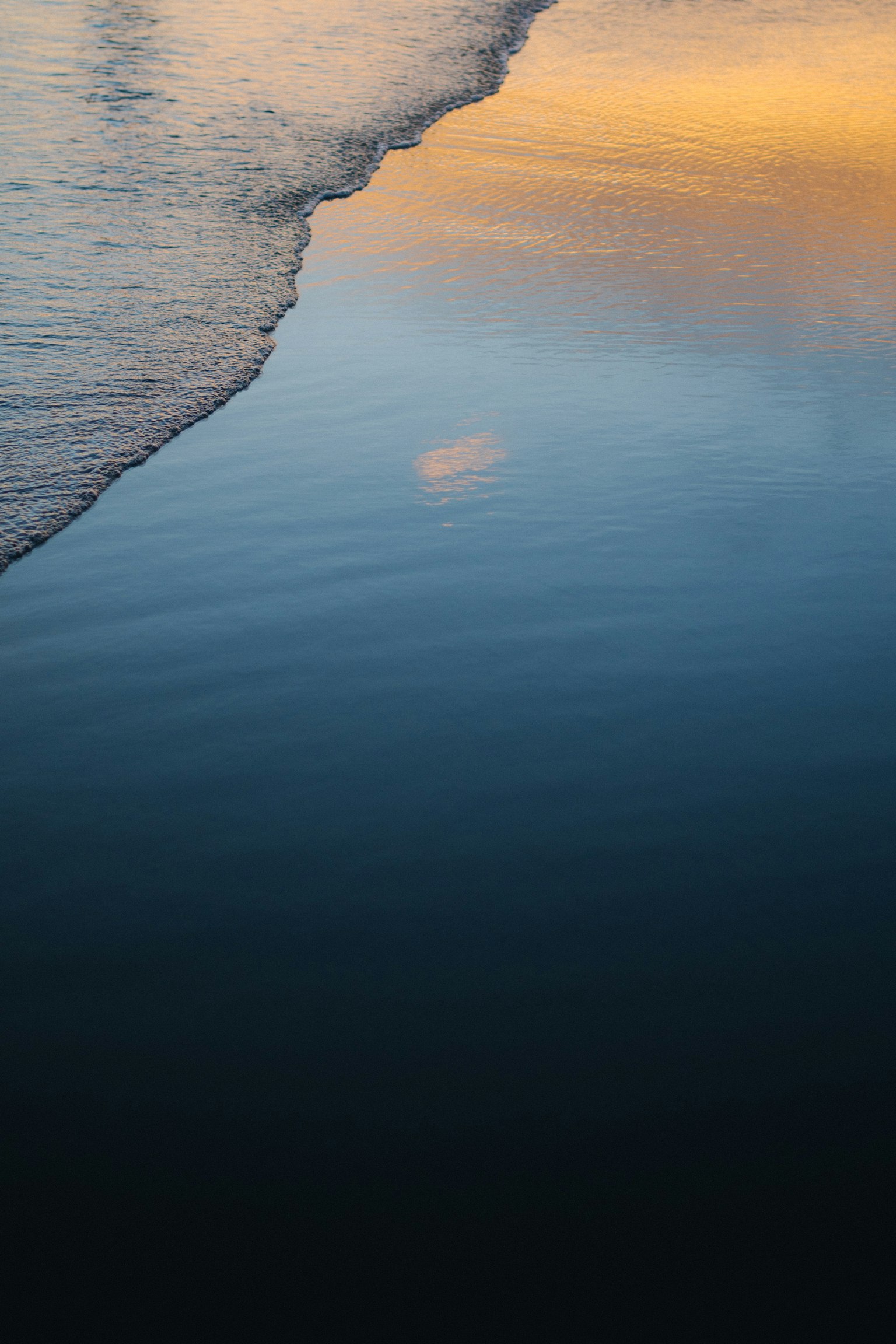 Sonnenuntergangsreflexion auf ruhigem Ozeanwasser mit sanfter Welle