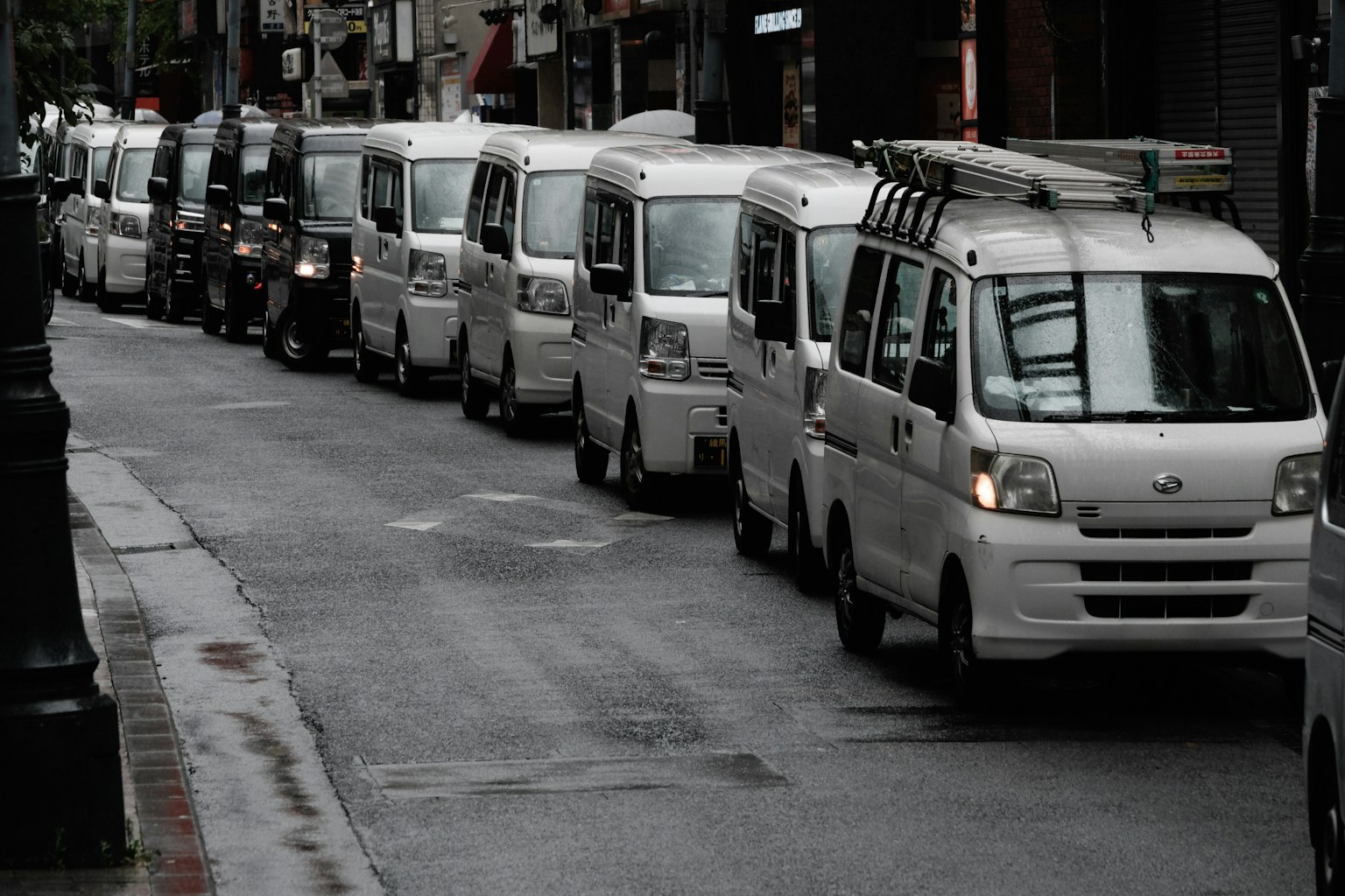 Une rangée de fourgonnettes blanches garées sur une rue mouillée