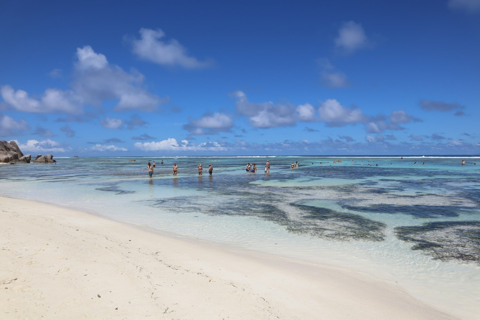 A scenic beach with blue sky and clear water where people are enjoying