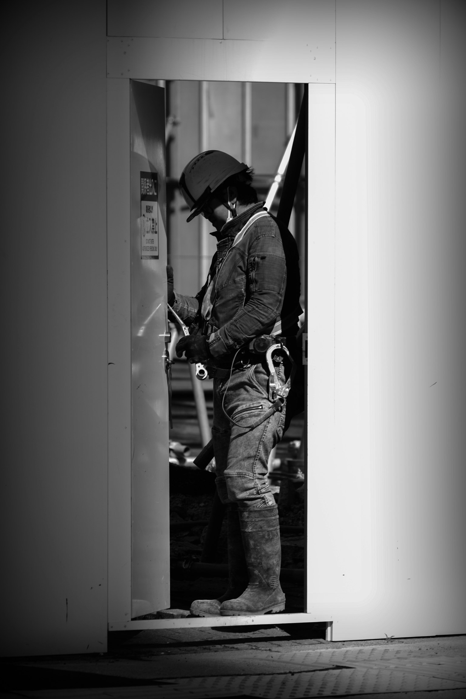 Un trabajador de pie en una puerta ajustando el equipo en contraste blanco y negro