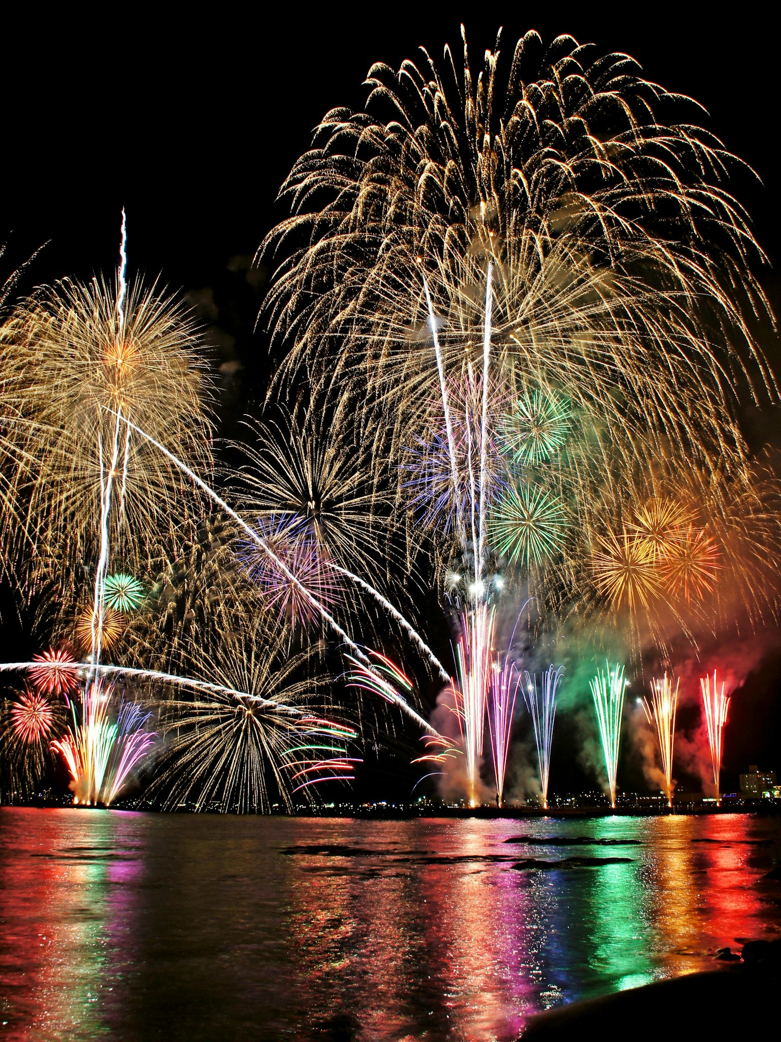 Fuochi d'artificio colorati che esplodono nel cielo notturno sopra l'acqua