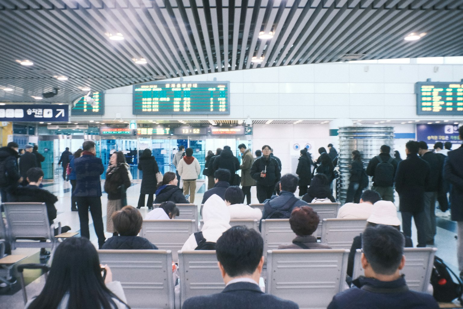 공항 대기실에 있는 승객들과 출발 및 도착 보드