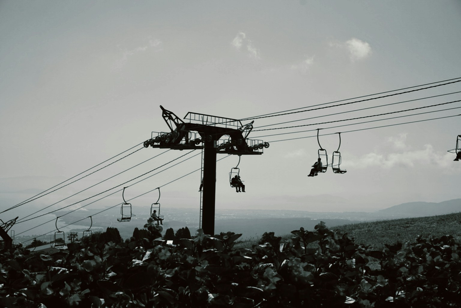 Black and white image of a ski lift with mountains in the background
