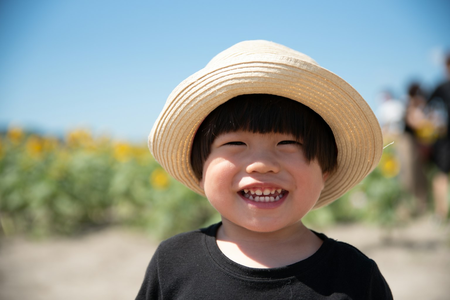 Bambino sorridente con un cappello di paglia sotto il sole