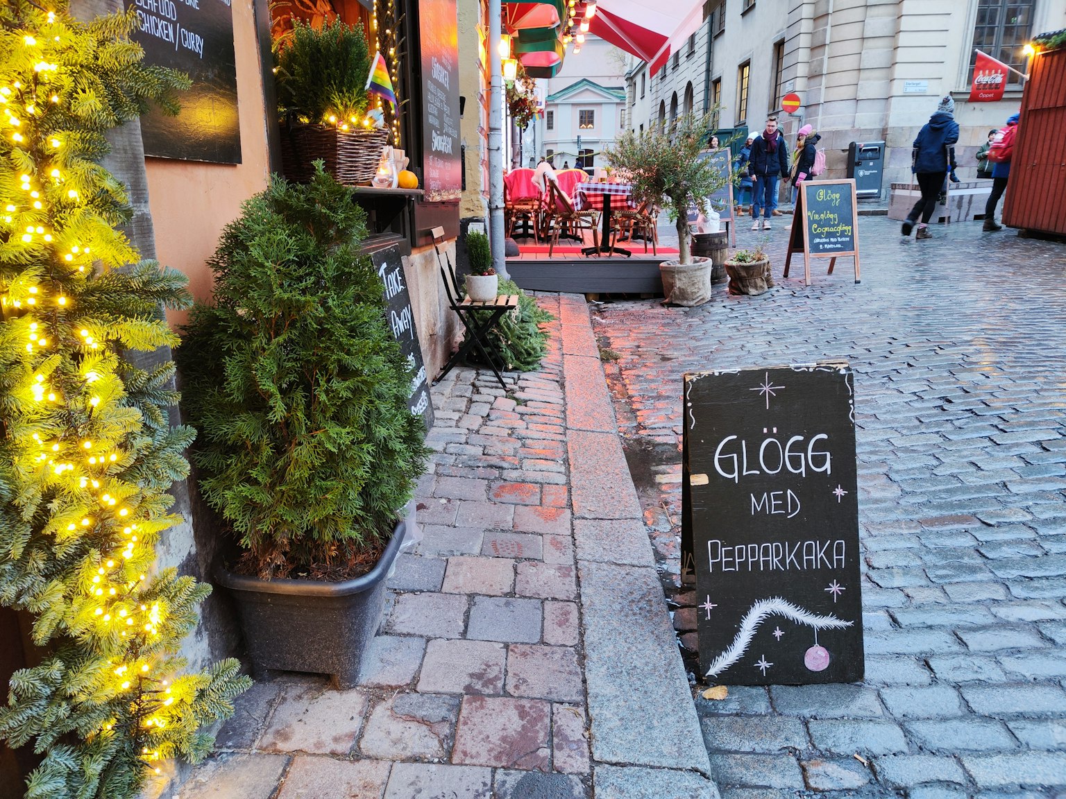 Scena di caffè all'aperto con un'insegna per glögg e pepparkaka circondata da decorazioni festive