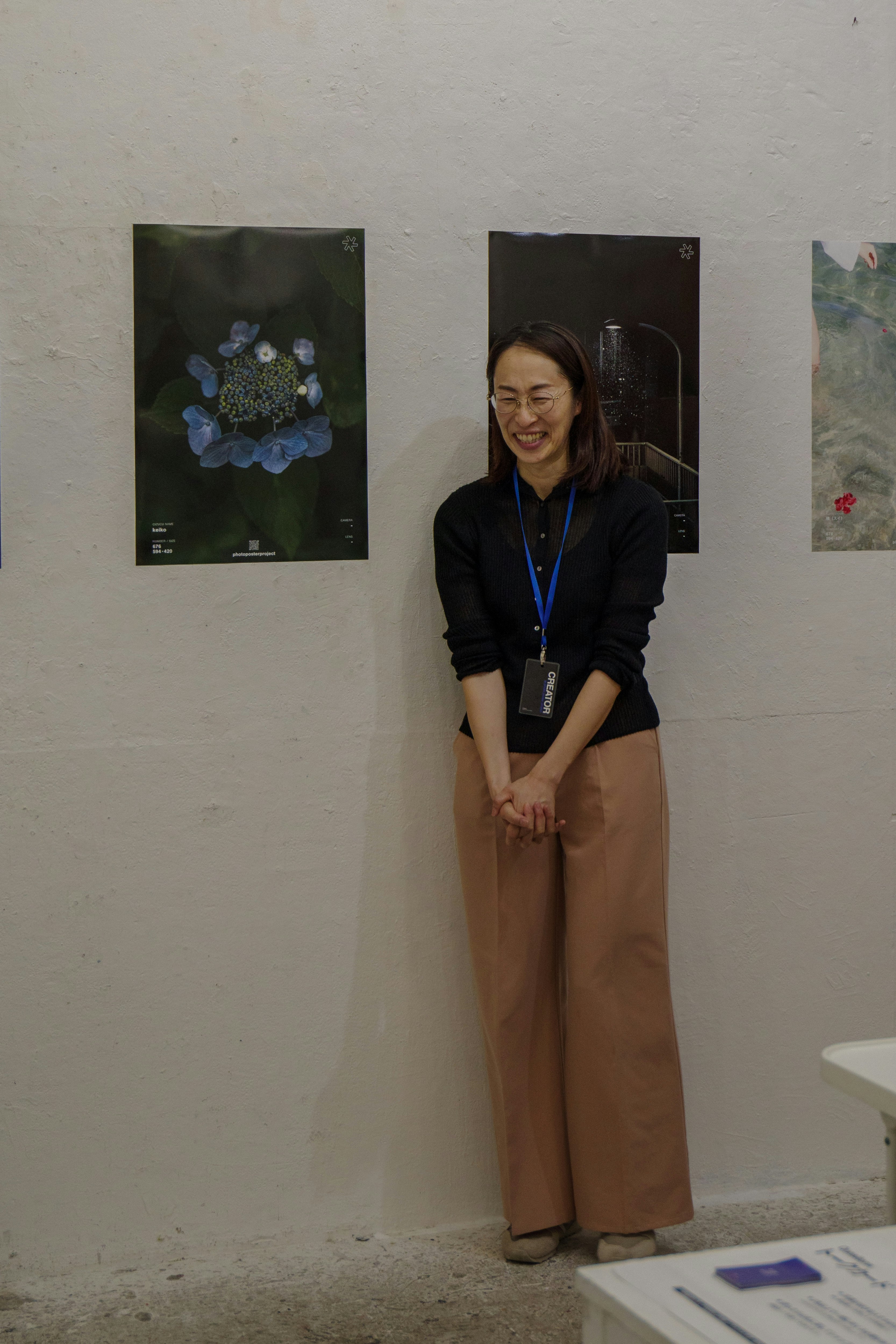 展示会場で壁に掛けられたアートポスターの前に立つ女性