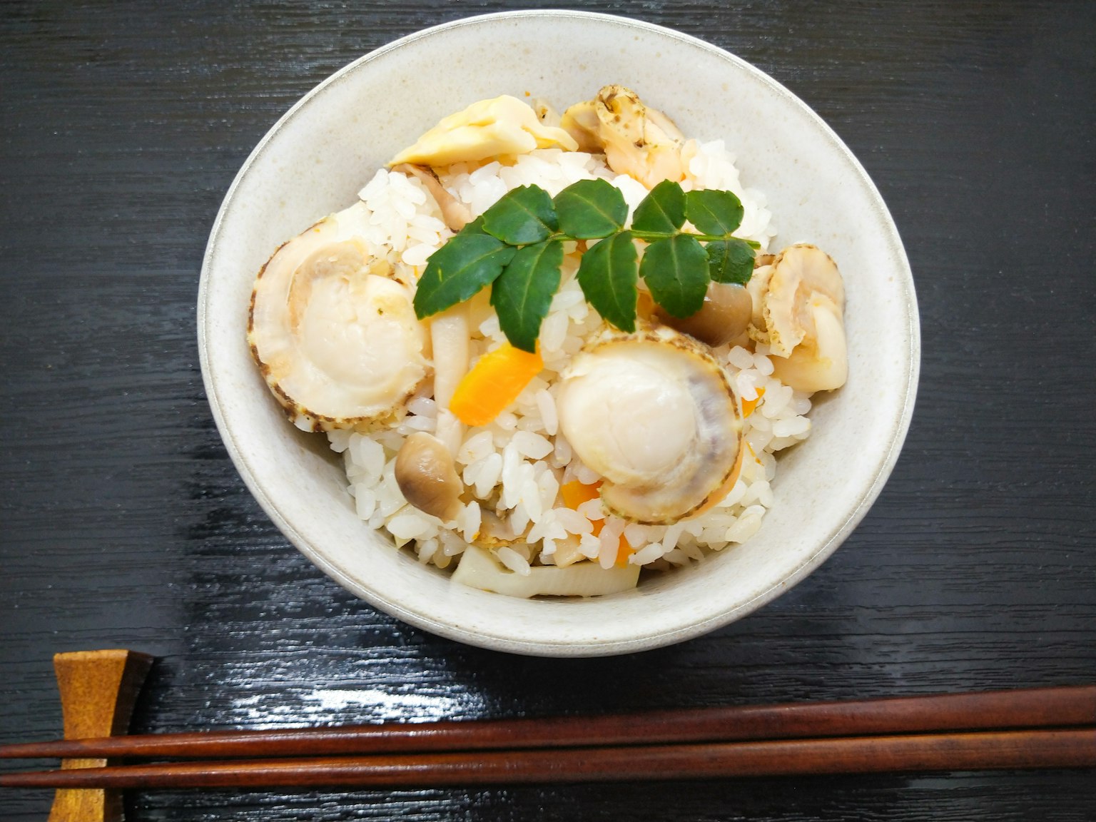 一碗米飯，上面放著扇貝和蔬菜