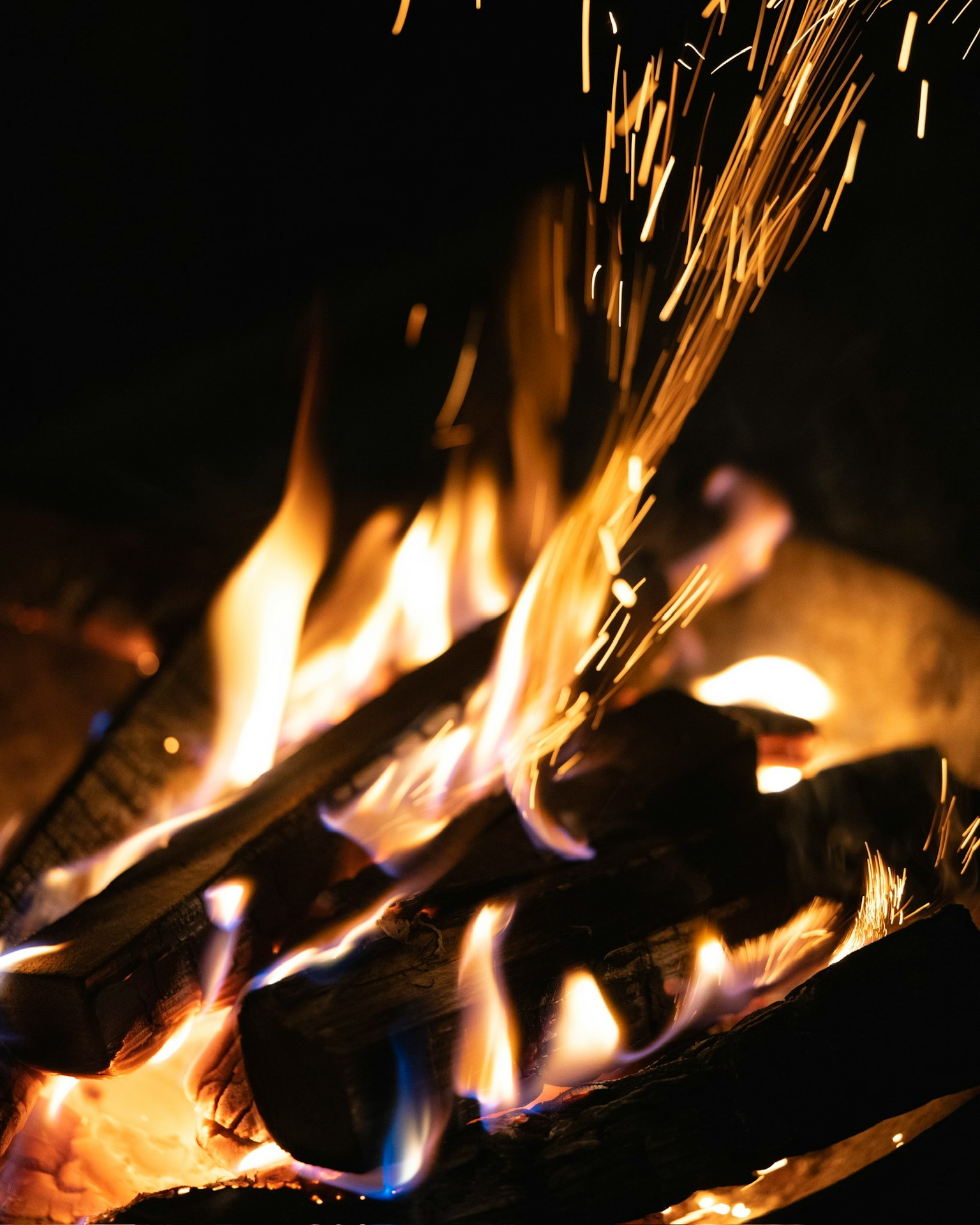 Flammes et étincelles s'élevant d'un feu de camp