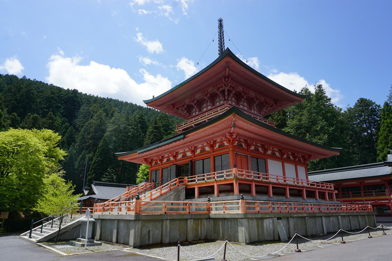 Temple japonais avec une pagode rouge entourée de verdure luxuriante et d'un ciel bleu