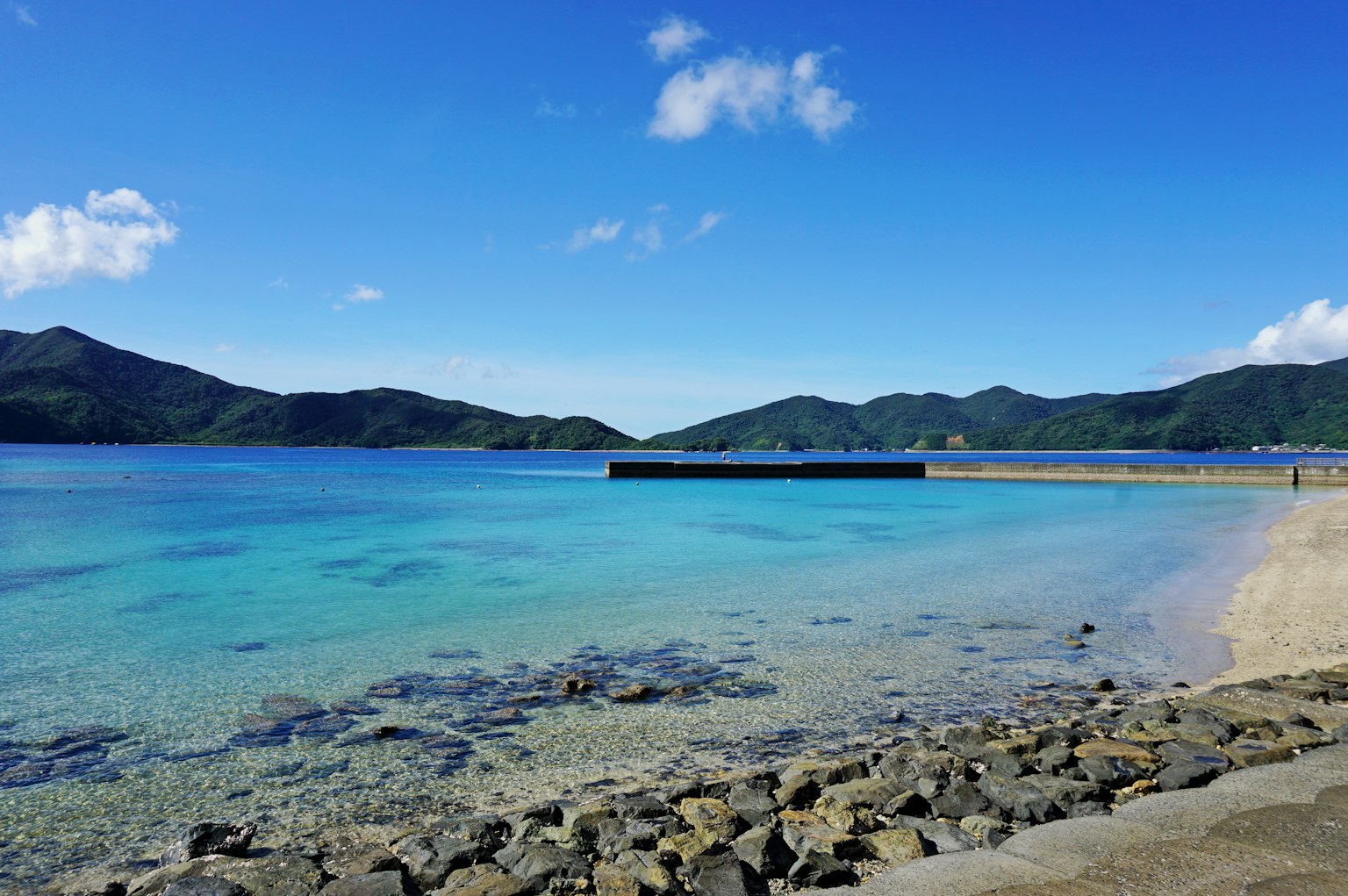 Pemandangan indah laut dan langit biru dengan garis pantai dan pegunungan
