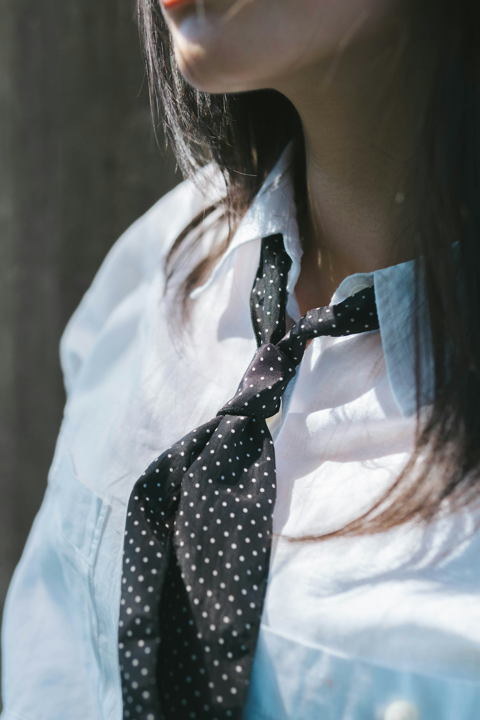 Primer plano de una mujer con camisa blanca y corbata negra con lunares