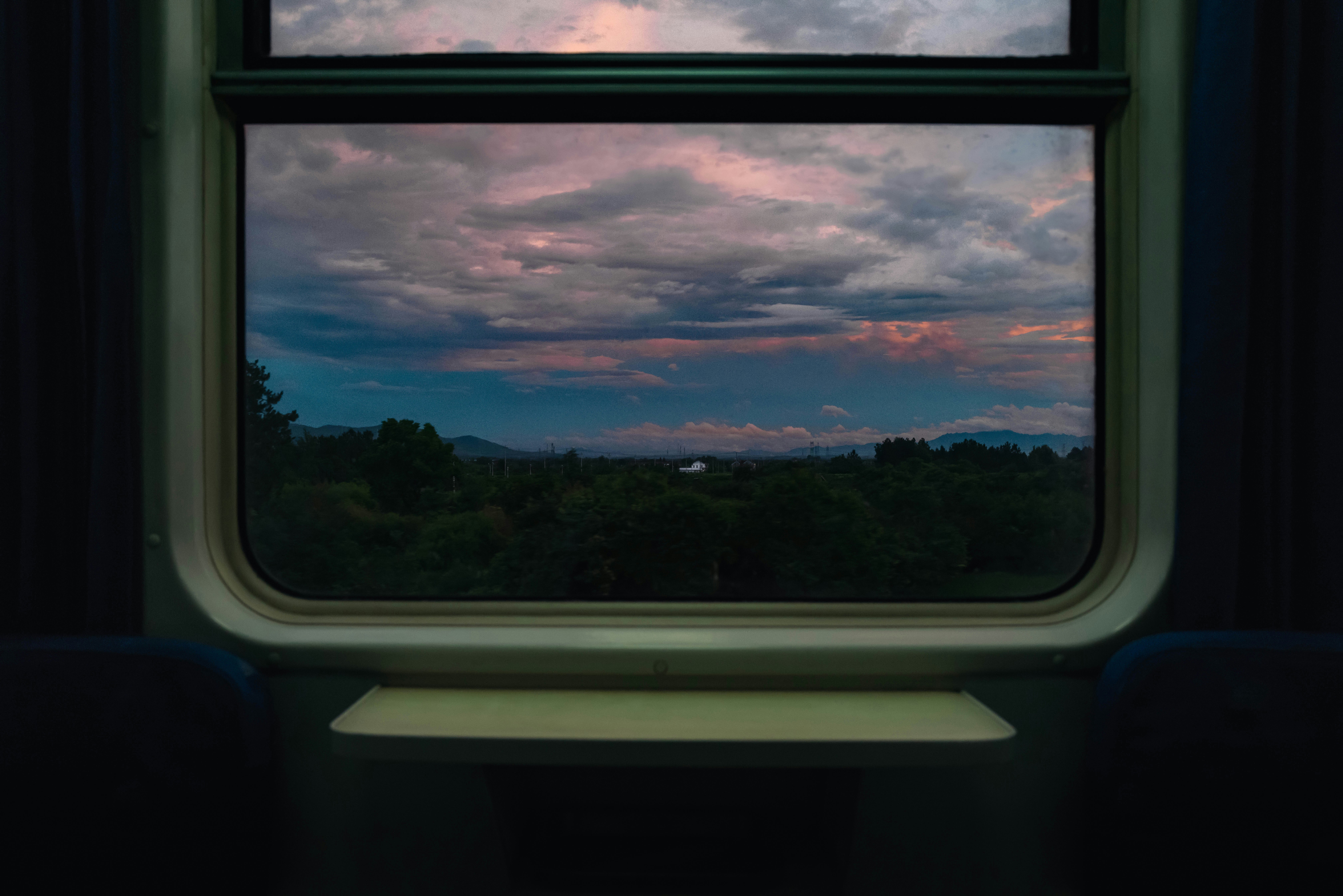 列車の窓から見える夕焼けの空と森の景色