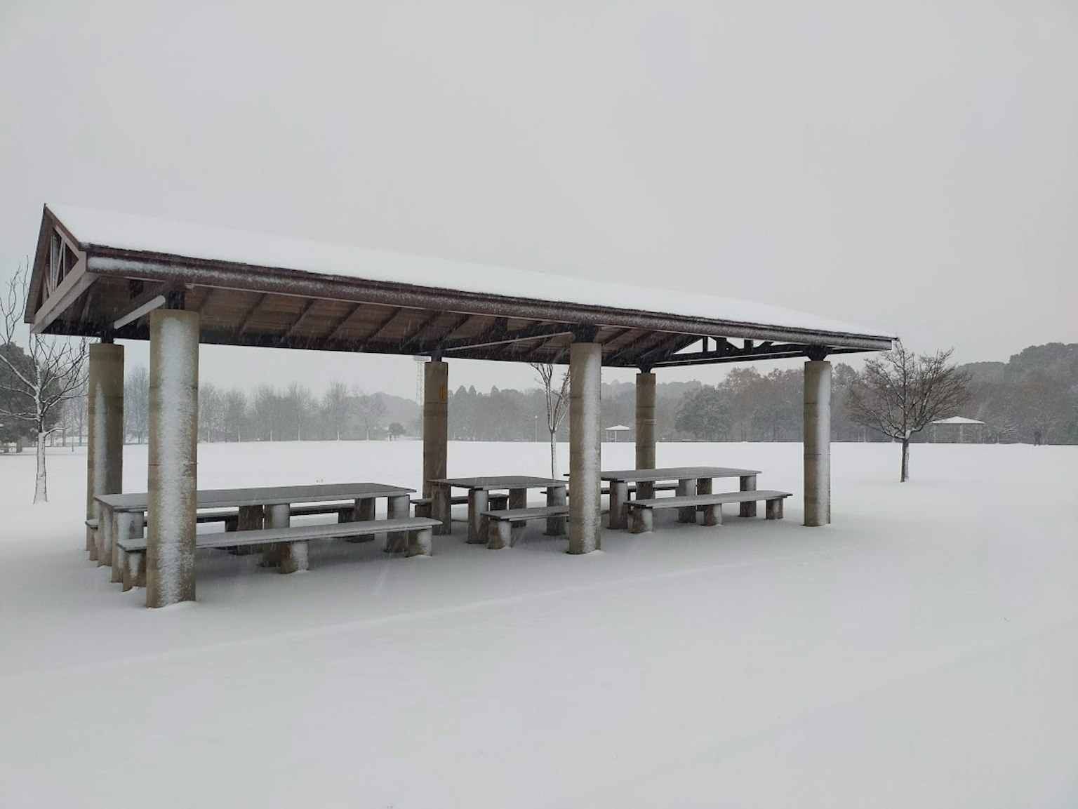 Schneebedeckter Pavillon mit Tischen in einem Park