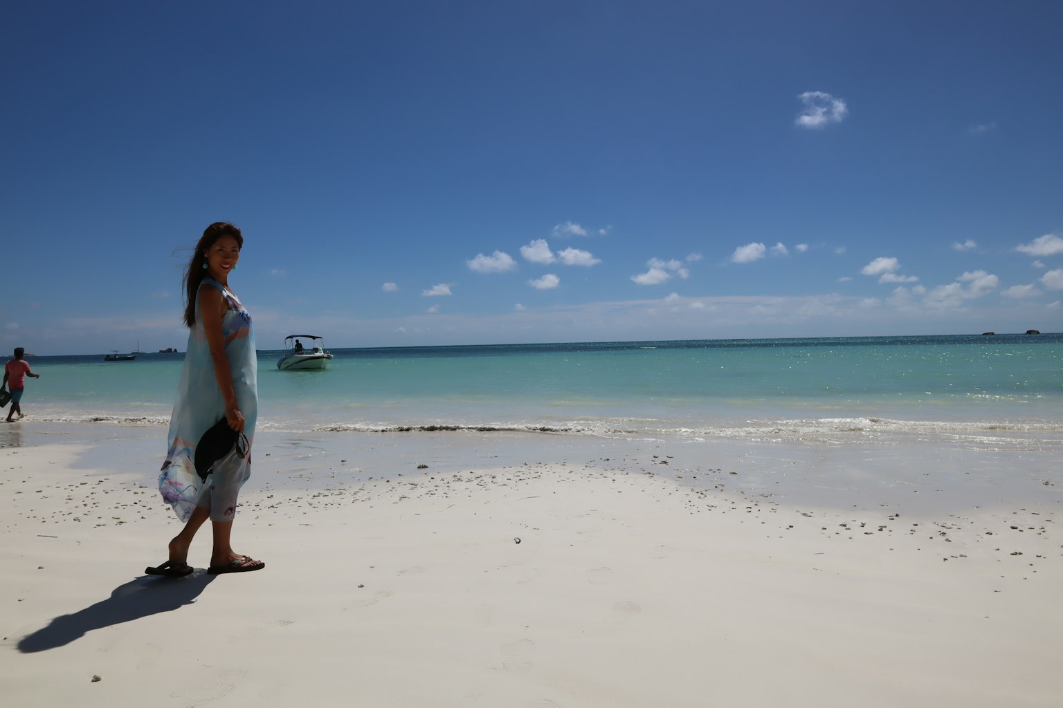 A woman standing on a beautiful beach with a blue ocean in the background