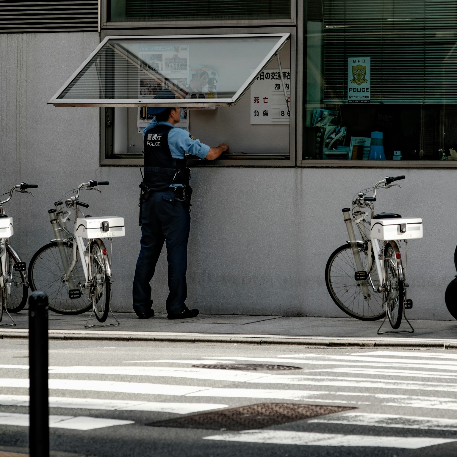 Un policier vérifiant des documents à une fenêtre avec des vélos garés à proximité