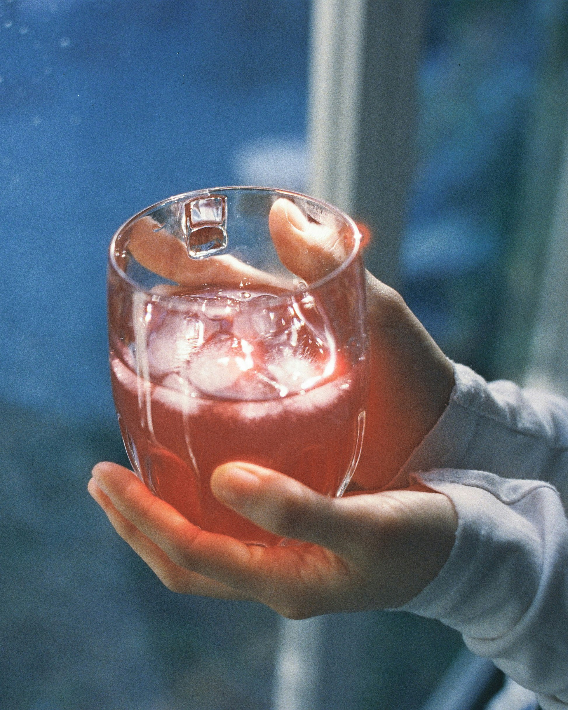 手のひらに注がれた氷入りの透明な飲み物