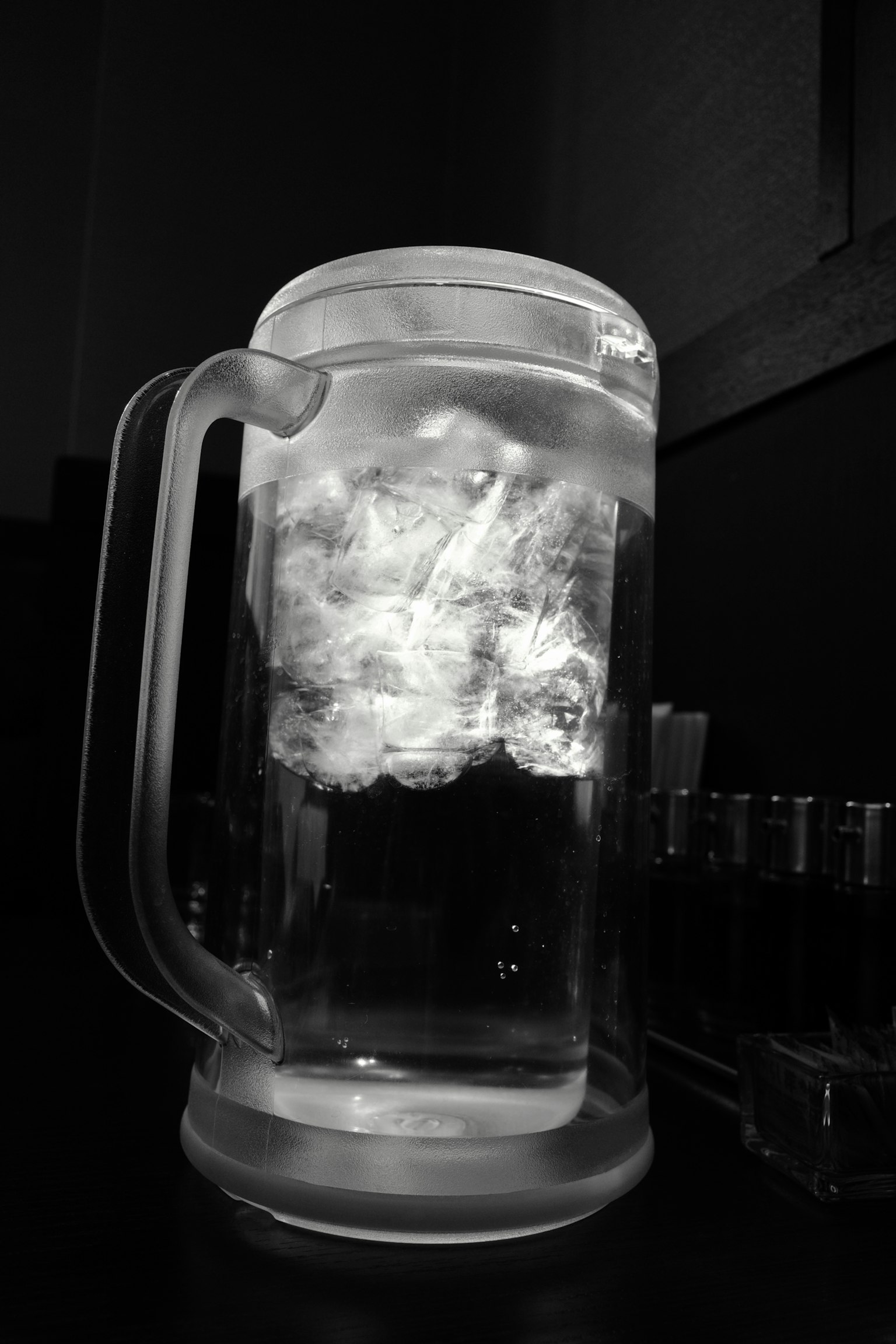 투명한 맥주 잔에 물과 떠 있는 얼음 조각이 담겨 있다
