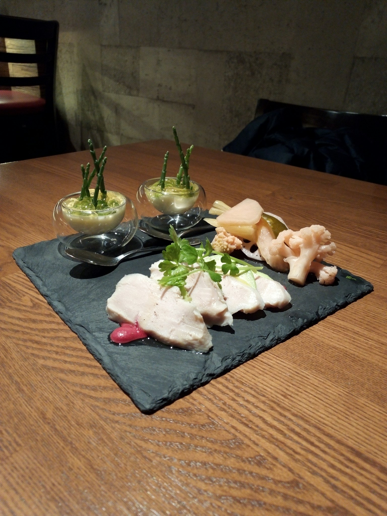 Platter of sliced chicken with garnishes on a slate plate