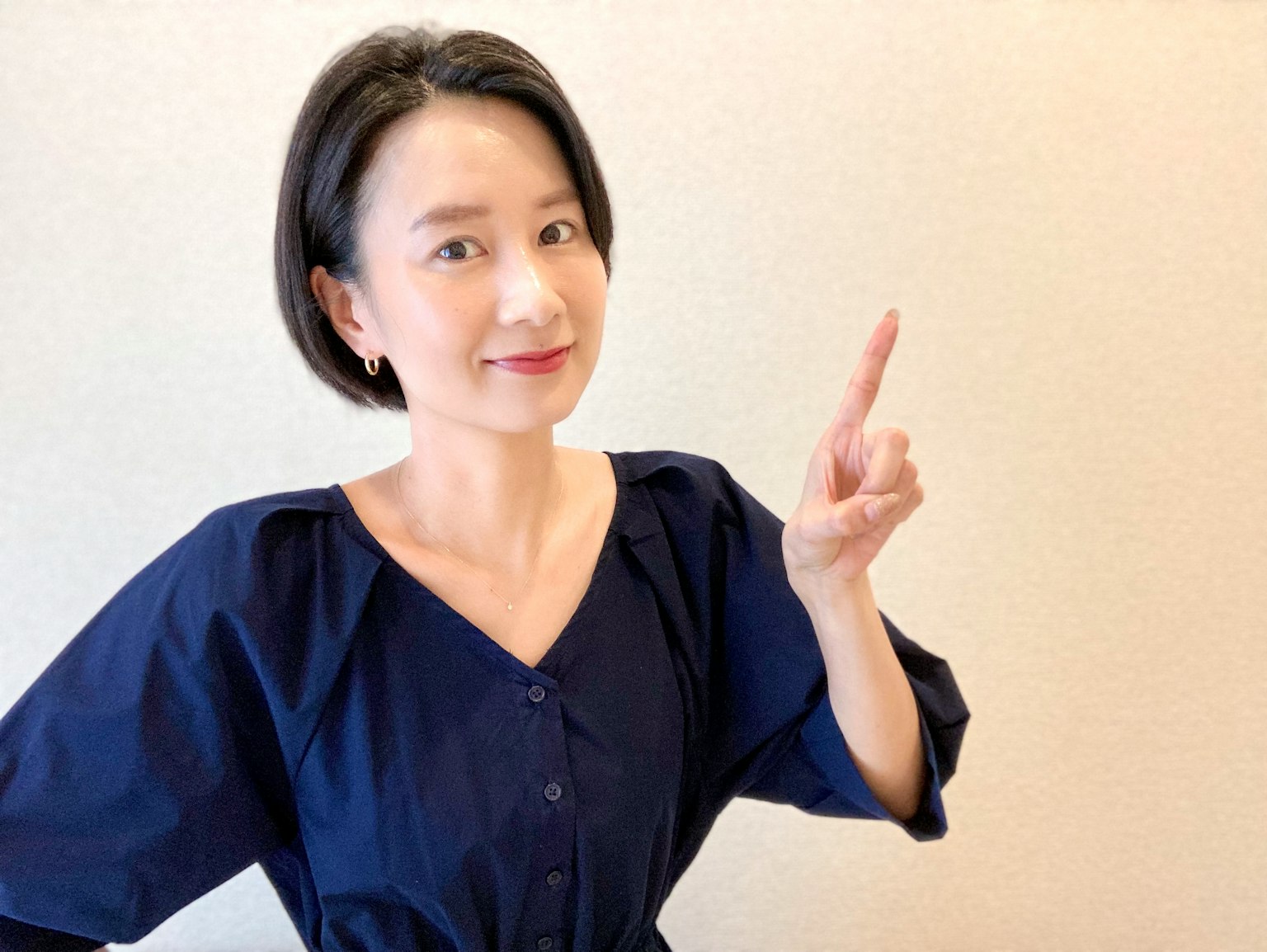 Una donna in abbigliamento blu che sorride e punta con il dito