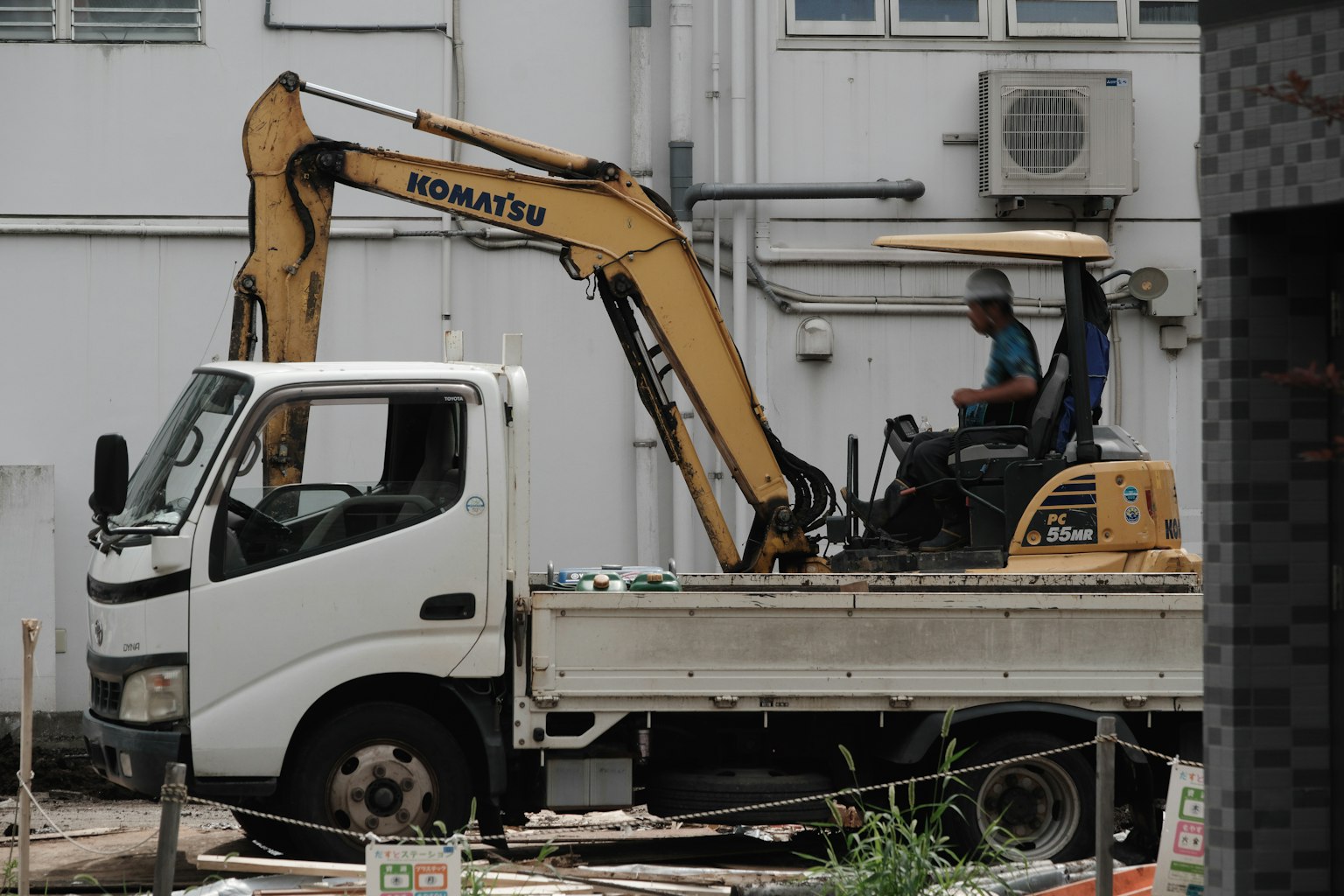 Opérateur assis sur une excavatrice jaune montée sur un camion blanc