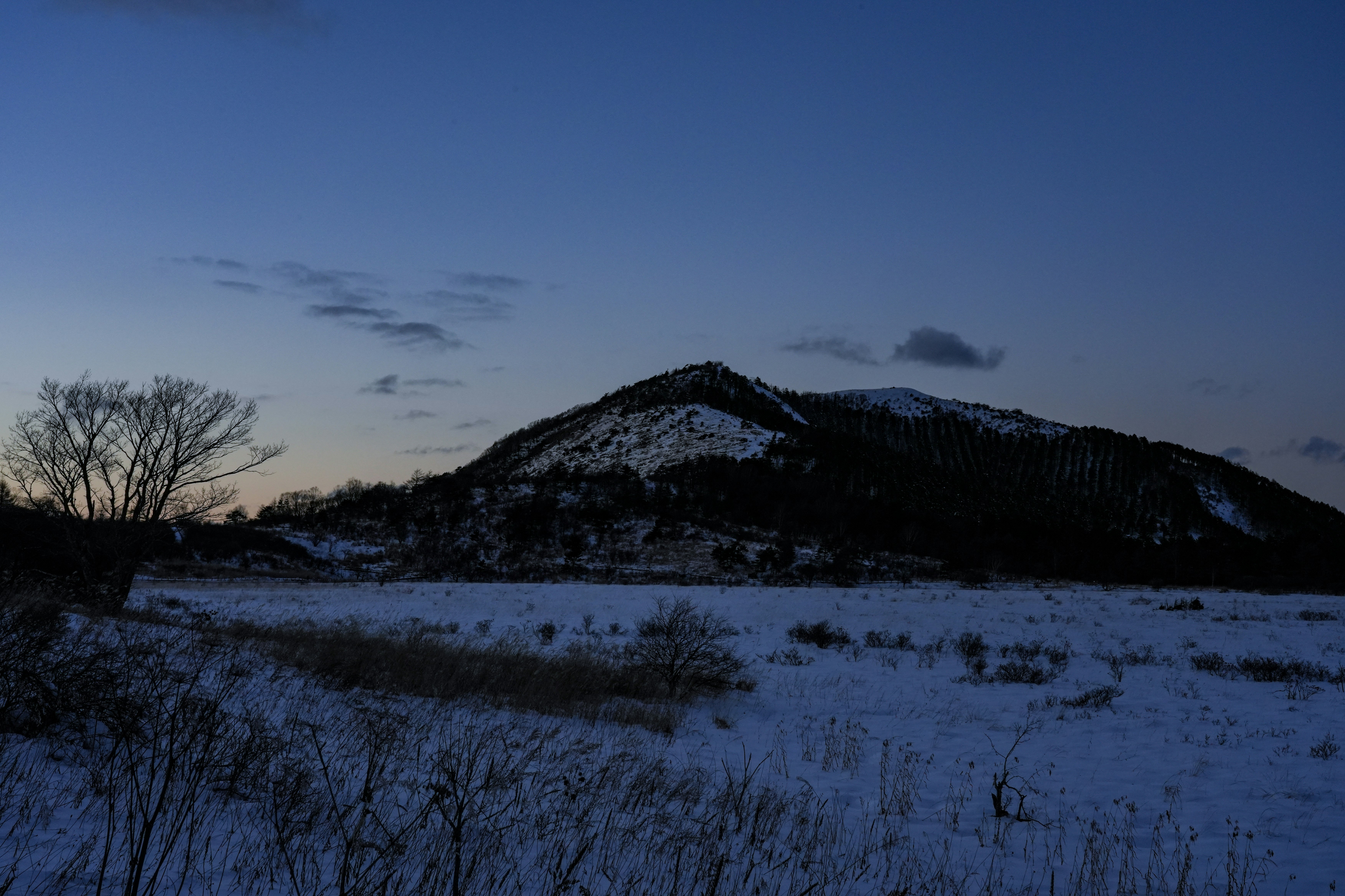 雪の積もる丘と山並みの夕暮れの風景