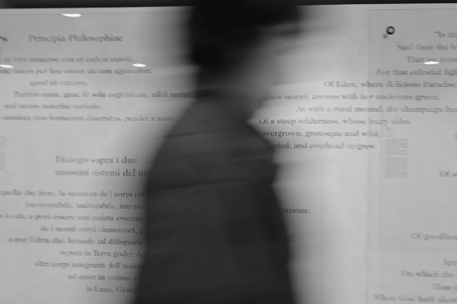 動いている人のシルエットが背景のテキストと対比しているモノクロ画像