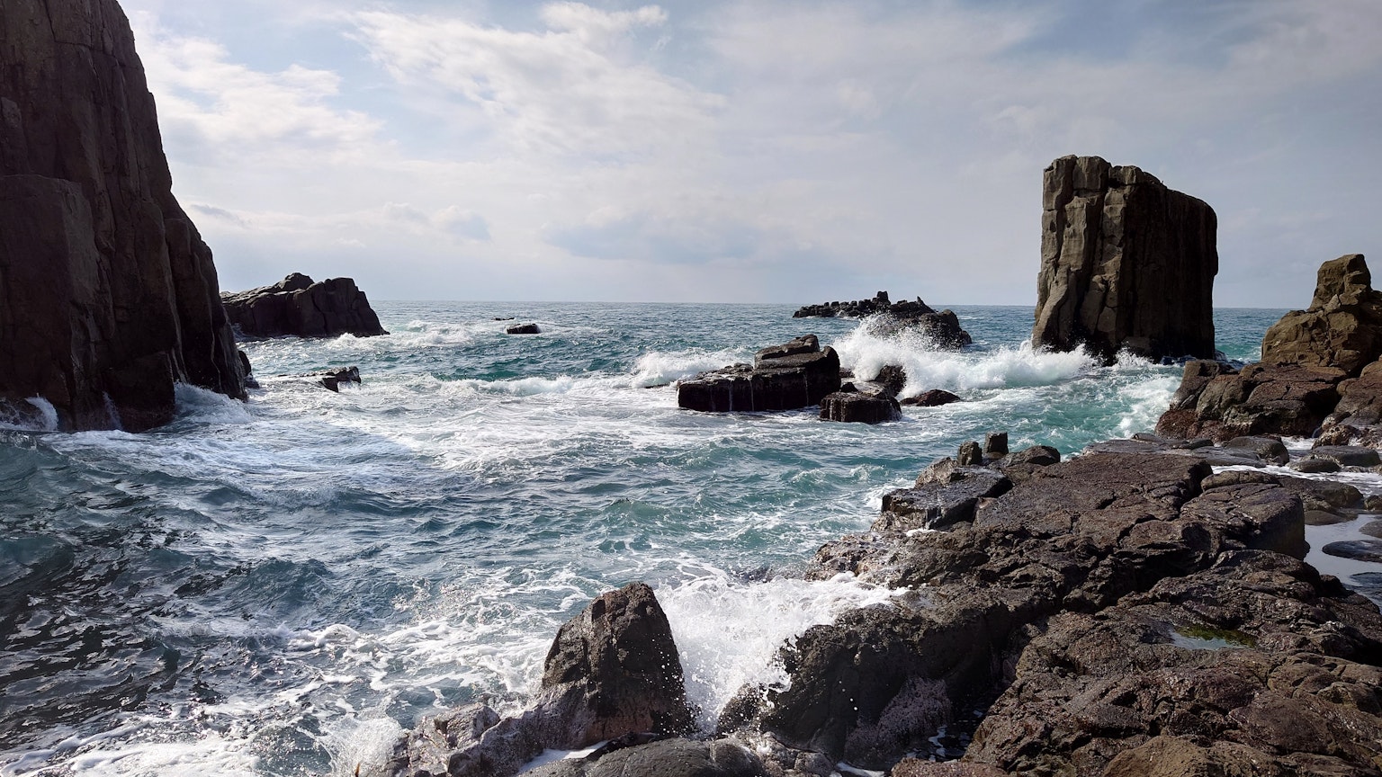 Rauhe Küste mit brechenden Wellen an Felsen