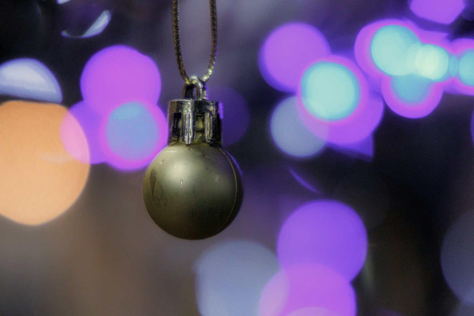 Einfacher Weihnachtsornament hängt vor einem lila Bokeh-Hintergrund