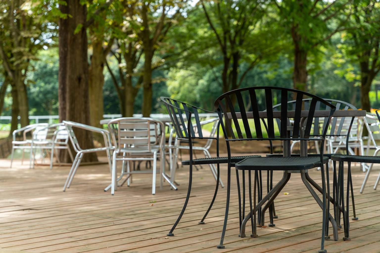 녹색 나무로 둘러싸인 나무 데크에 놓인 검은색과 흰색 의자
