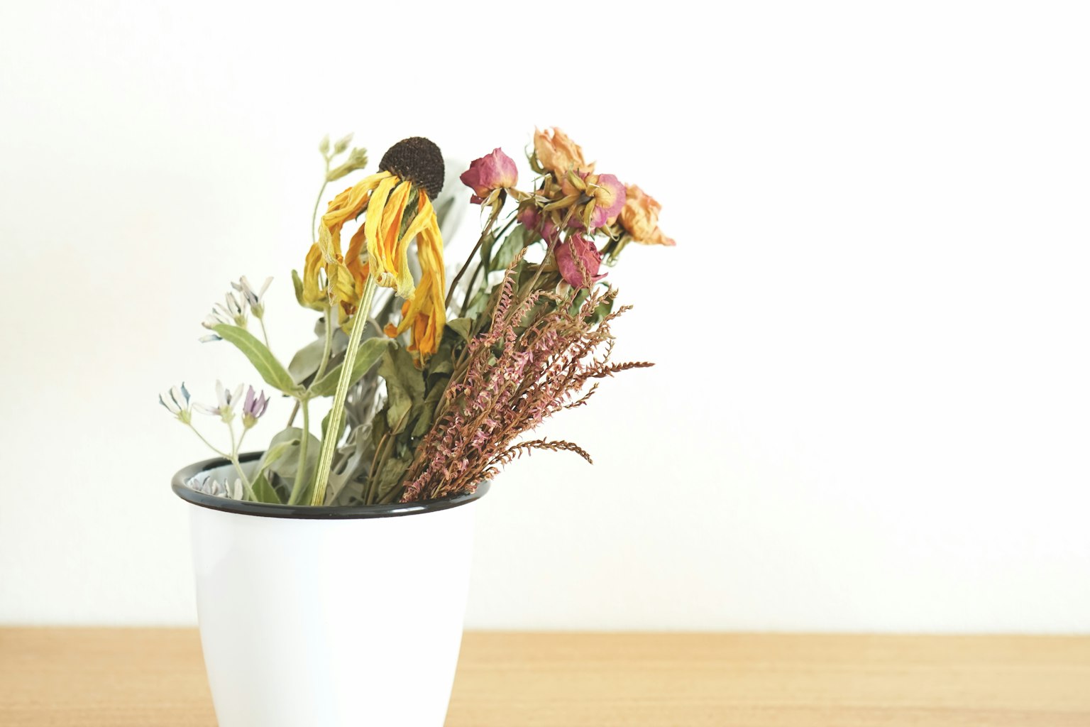 Arrangement de fleurs séchées dans un vase blanc sur fond blanc