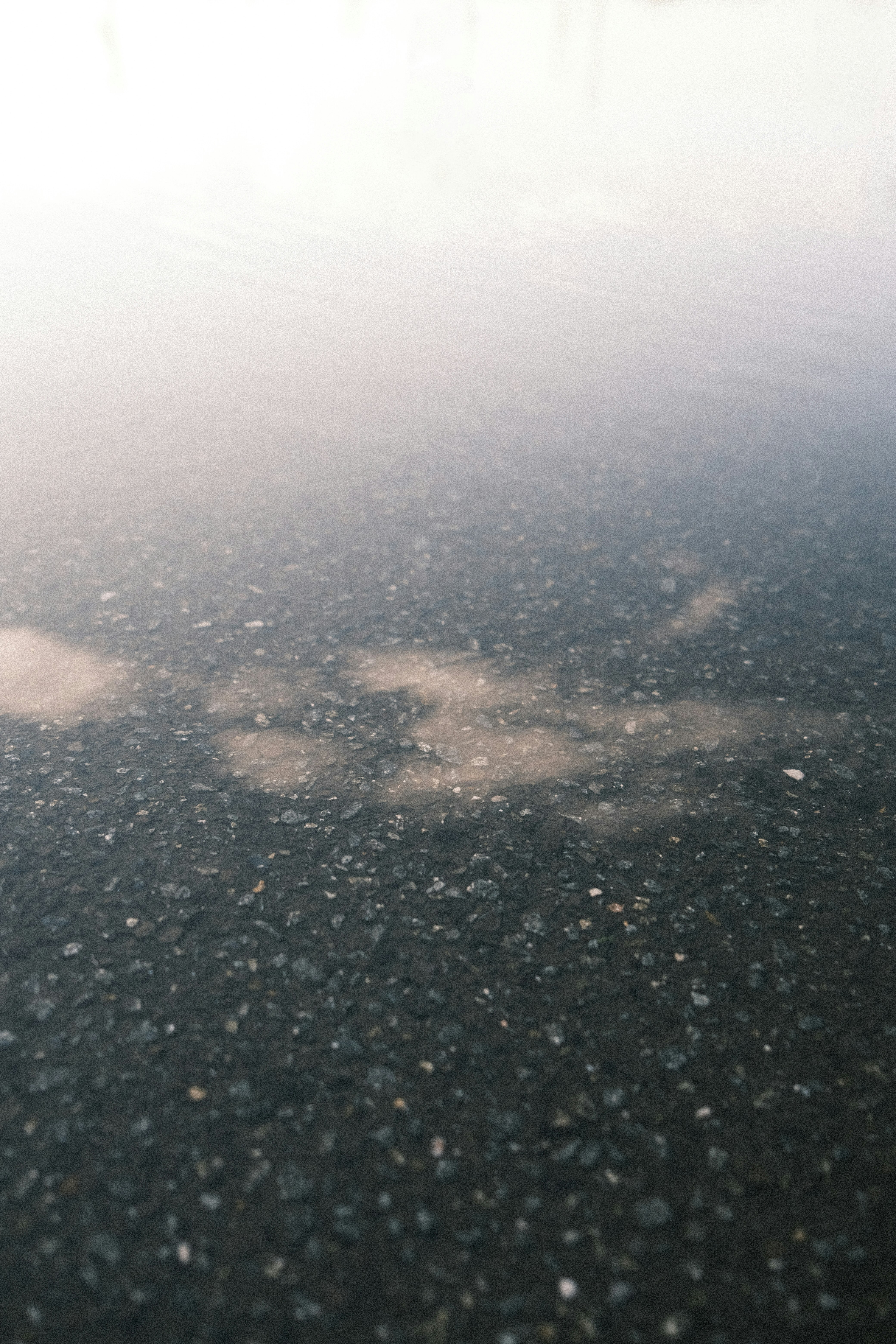 雨上がりの濡れた路面に映る雲の幻想的な水たまり