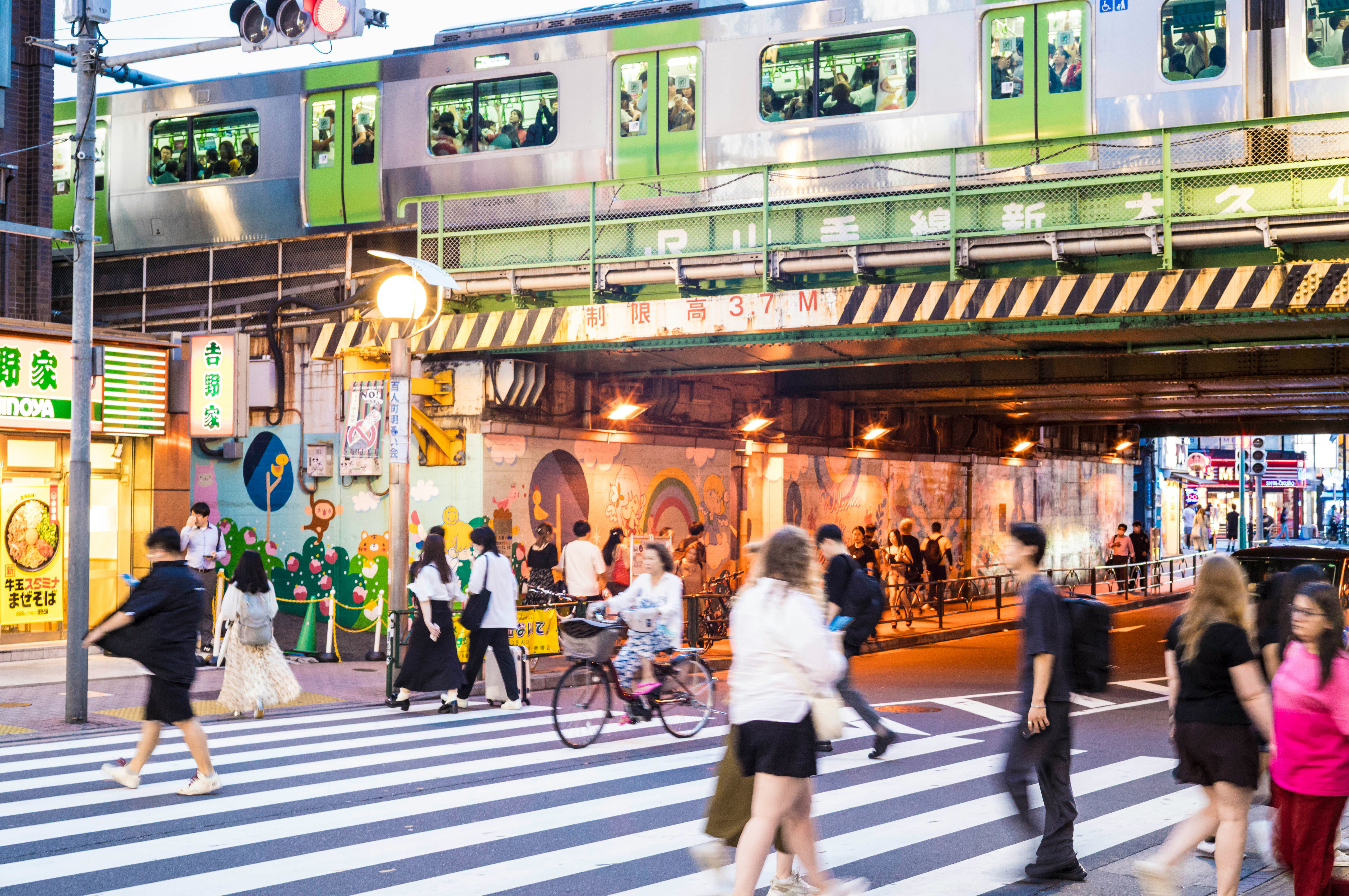 高架下の駅前通りを行き交う人々と自転車
