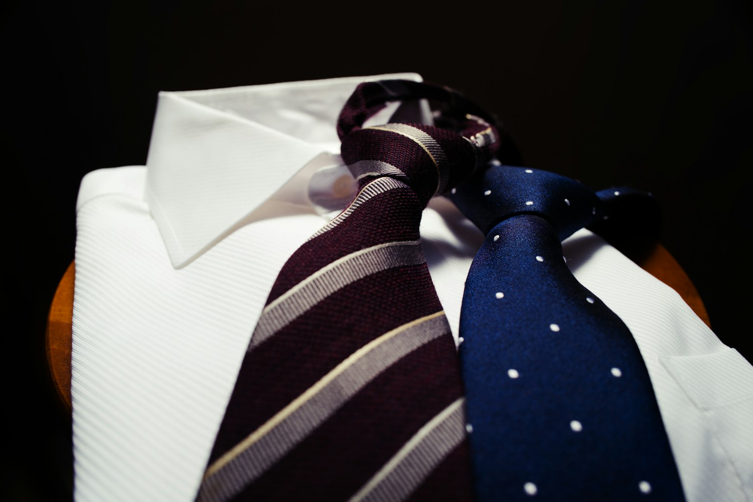 Striped and polka dot ties placed on a white shirt