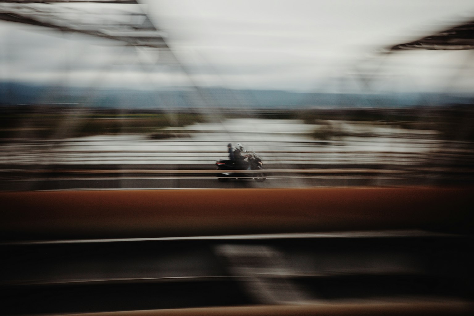 Sfondo sfocato con una moto in movimento e una struttura di ponte sopra l'acqua
