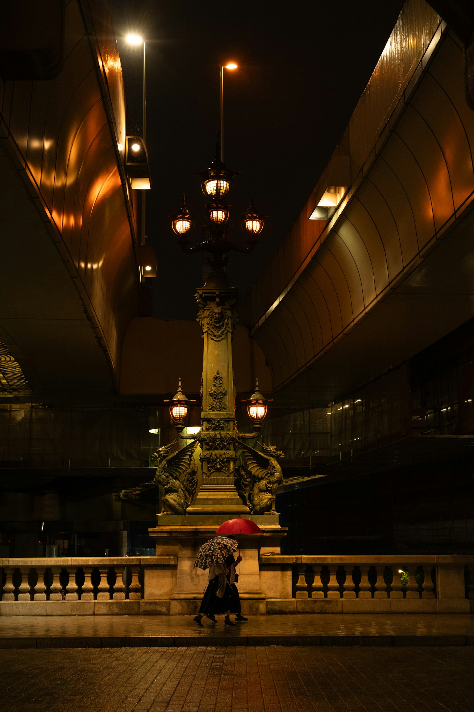 Une personne avec un parapluie dans un cadre urbain nocturne avec des lampadaires
