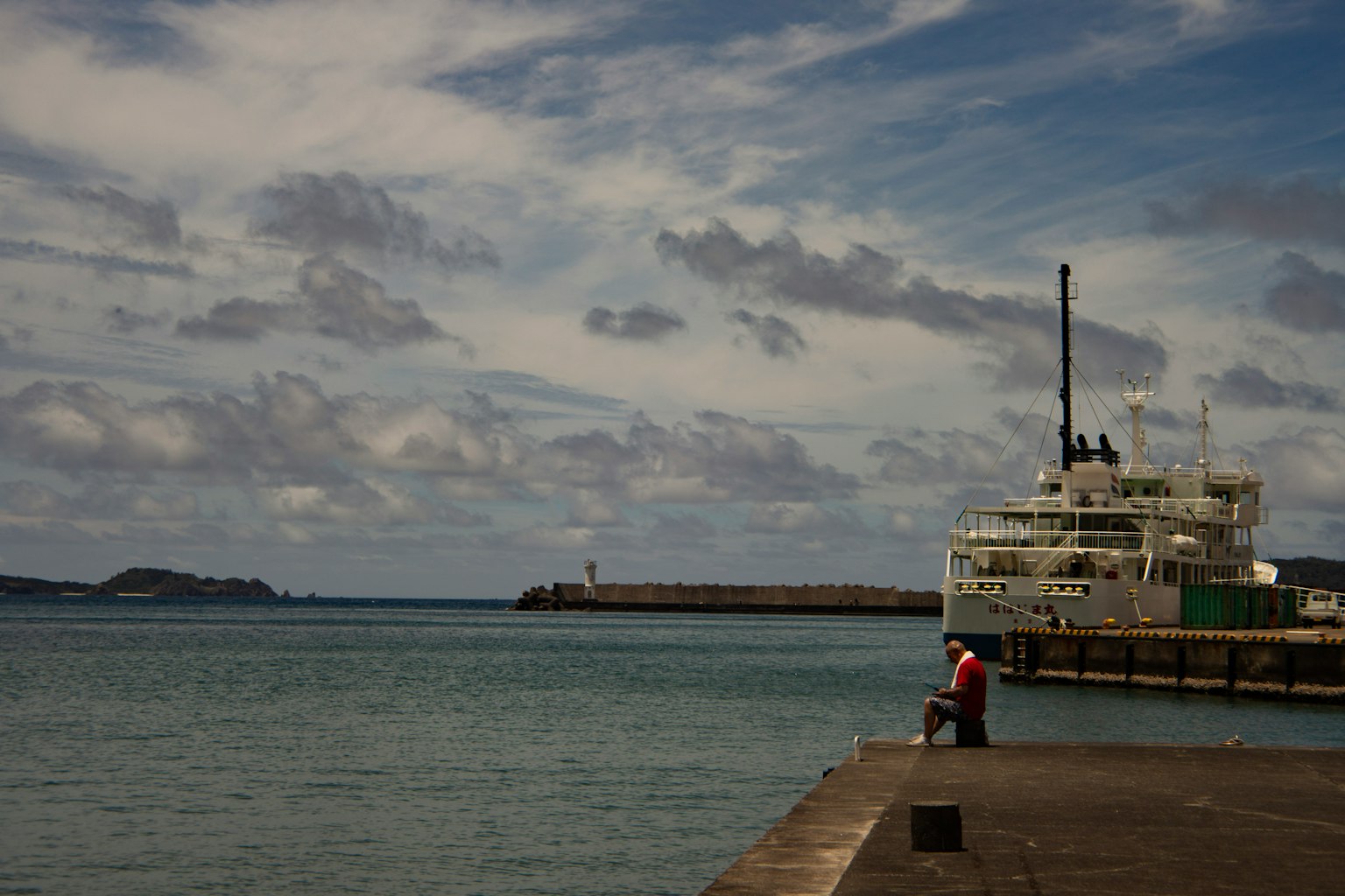 Una vista escénica de una persona en el puerto con un barco al fondo