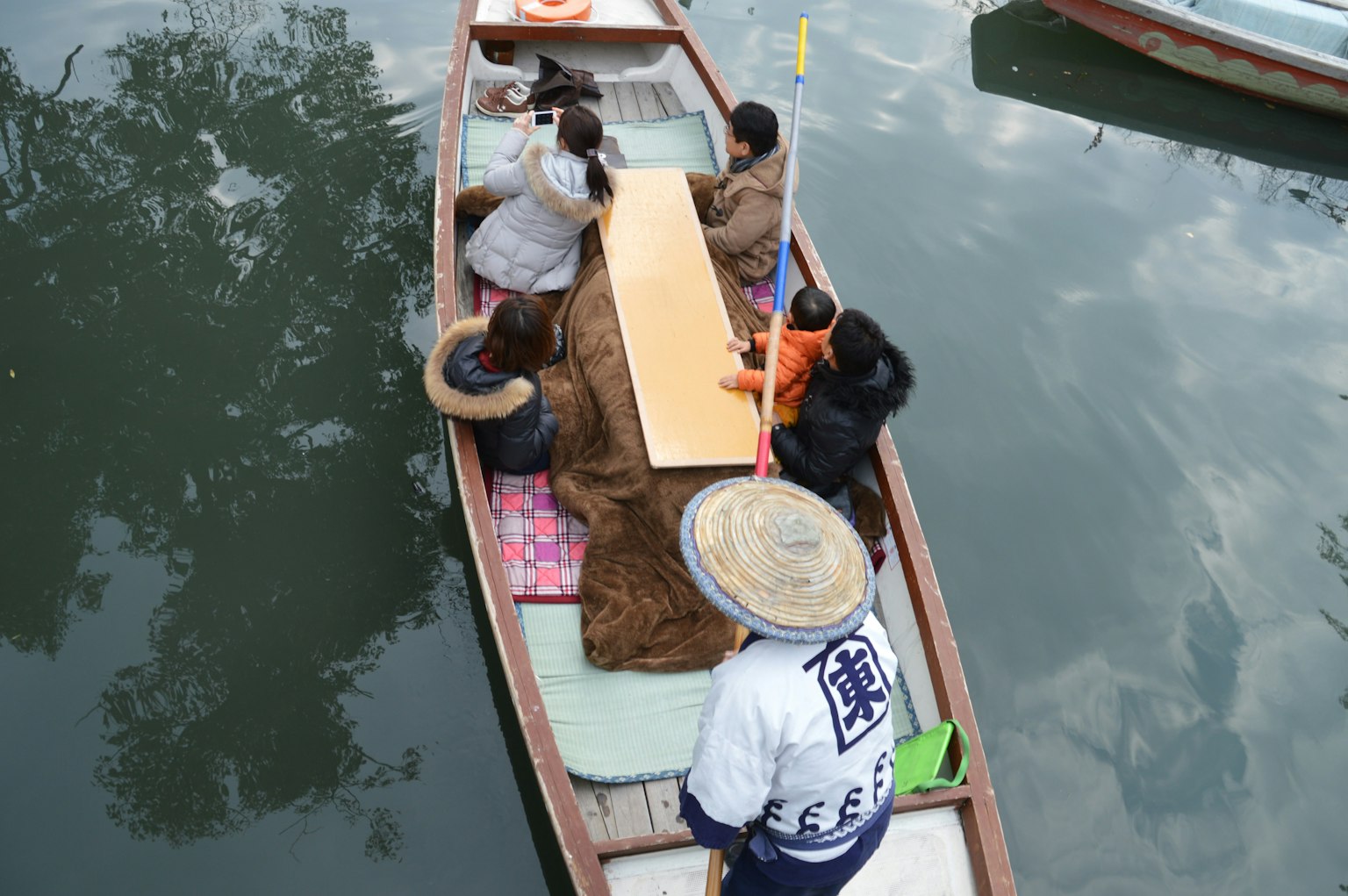 Sekelompok orang duduk di sekitar meja di perahu yang mengapung di sungai