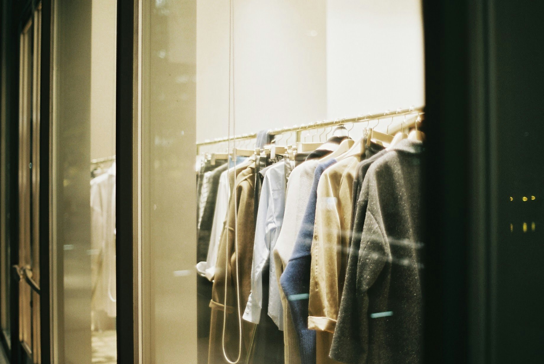 Close-up of clothing racks and hangers seen through a window