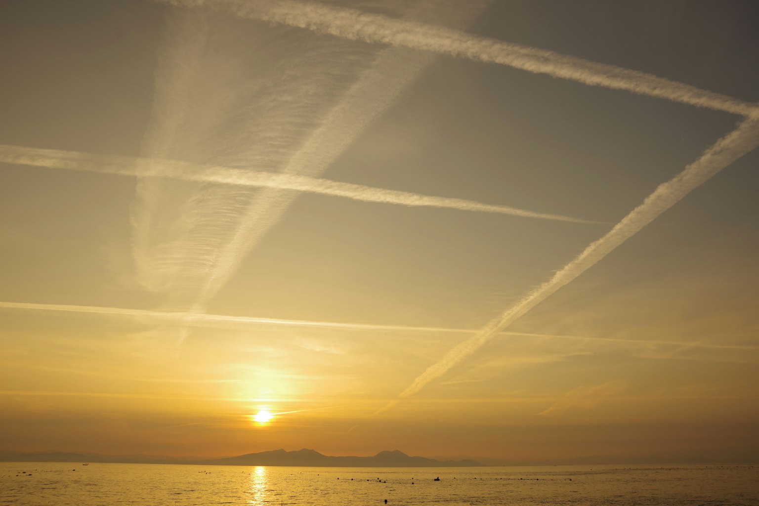 Tramonto con scie aeree che si incrociano nel cielo