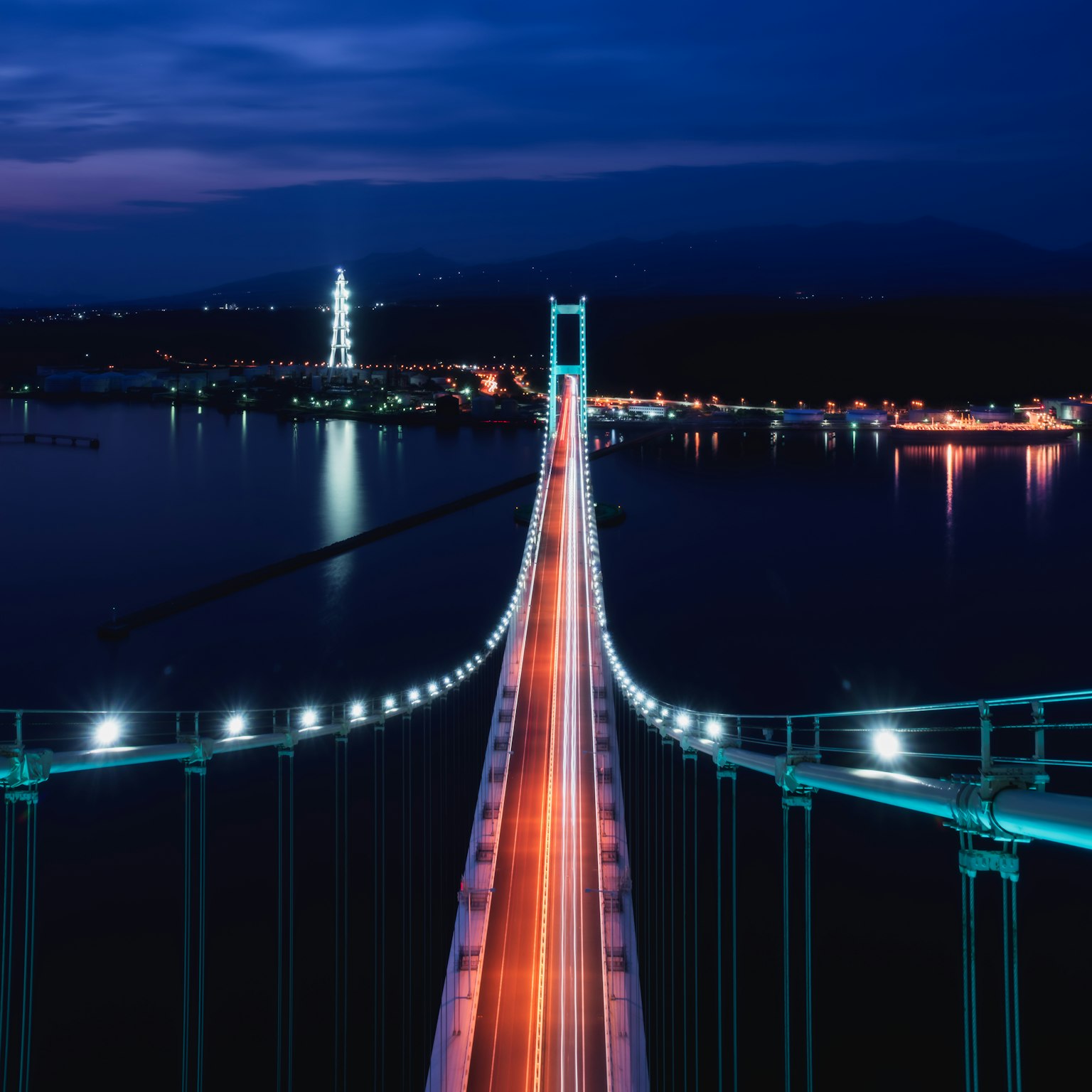 Impresionante vista nocturna de un puente iluminado por luces que se reflejan en el agua